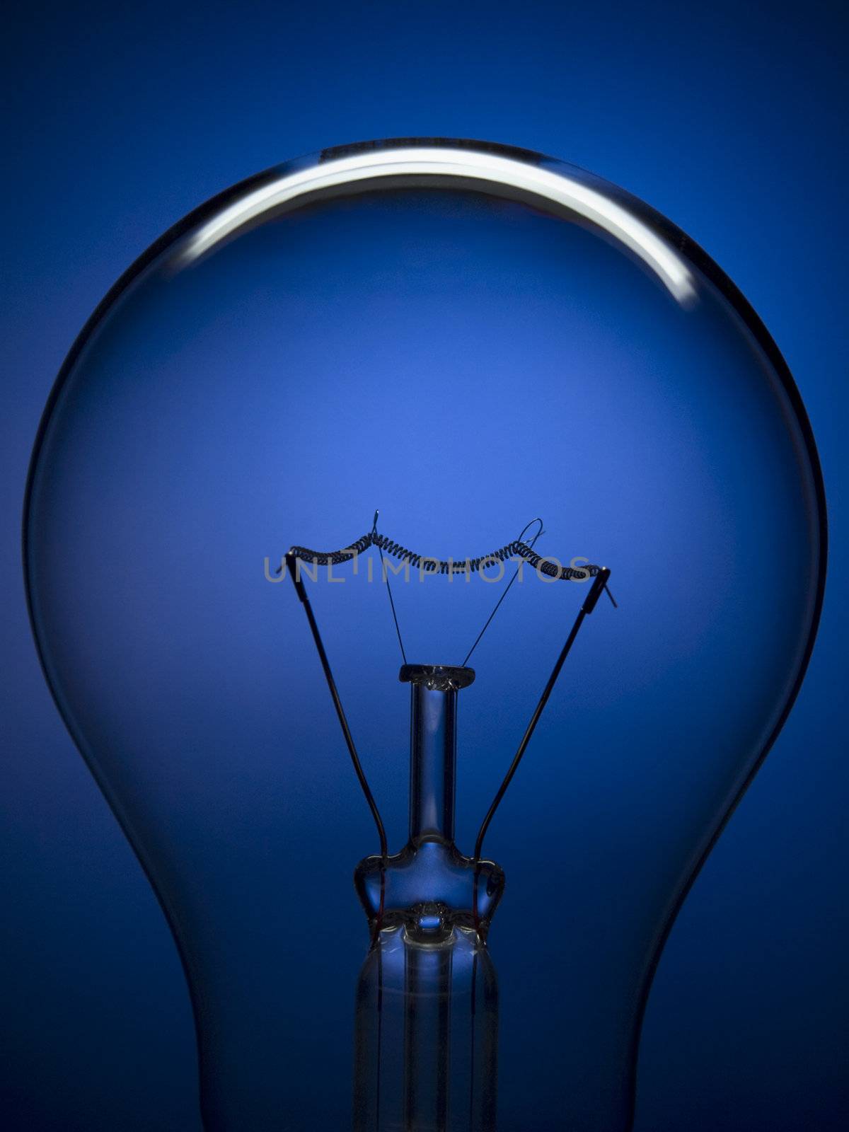 Close up on a transparent light bulb over a blue background.