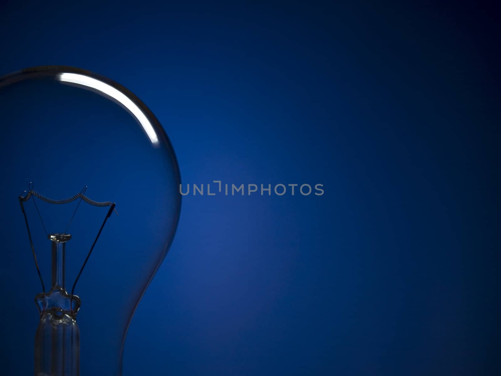 Close up on a transparent light bulb over a blue background. Copy space.