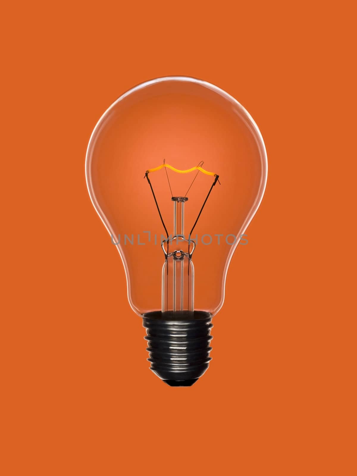 A transparent light bulb over an orange background. Tungsten glowing filament.