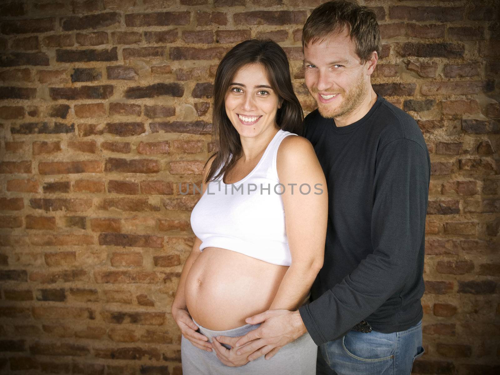 Pregnant young couple smiling at the camera.