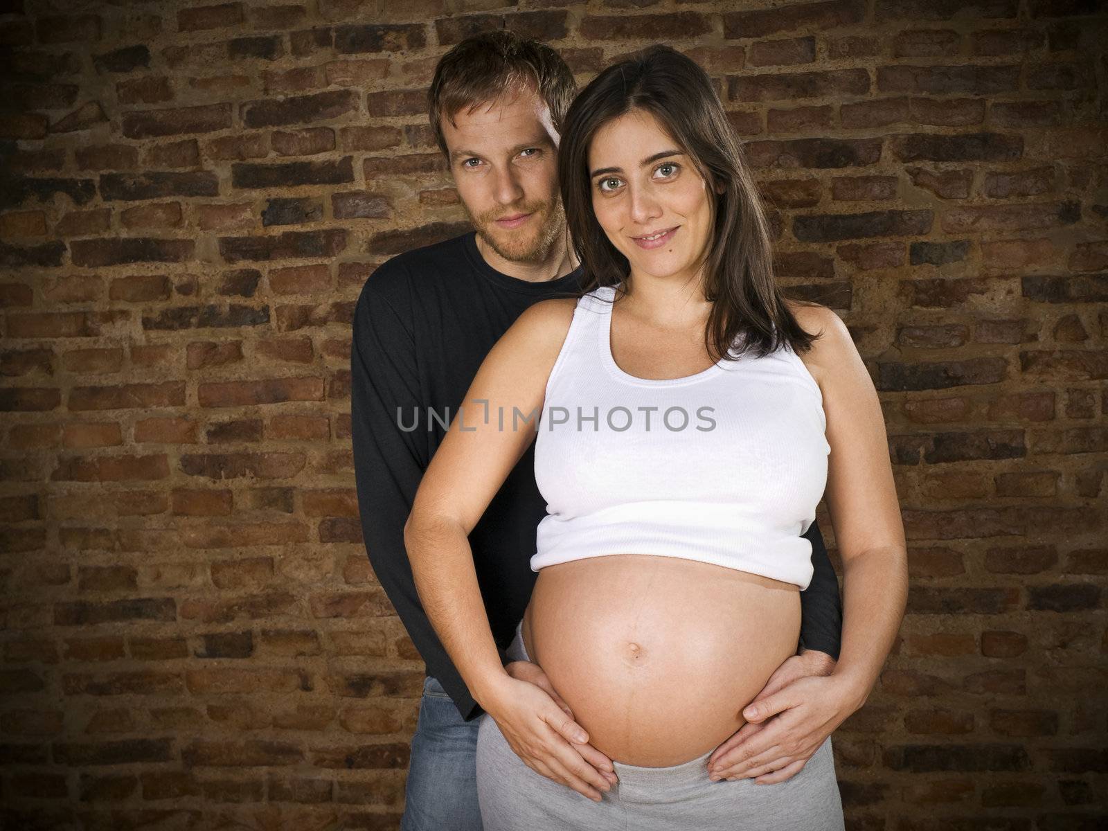Young couple holding the belly of the pregnant woman.