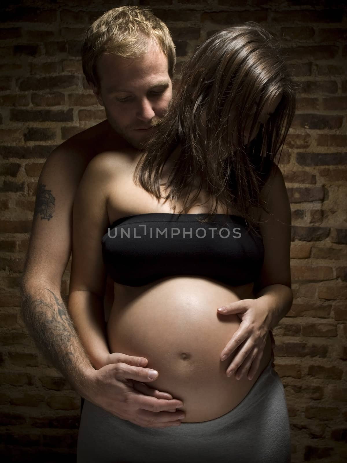 A man holding his pregnant wife's belly.