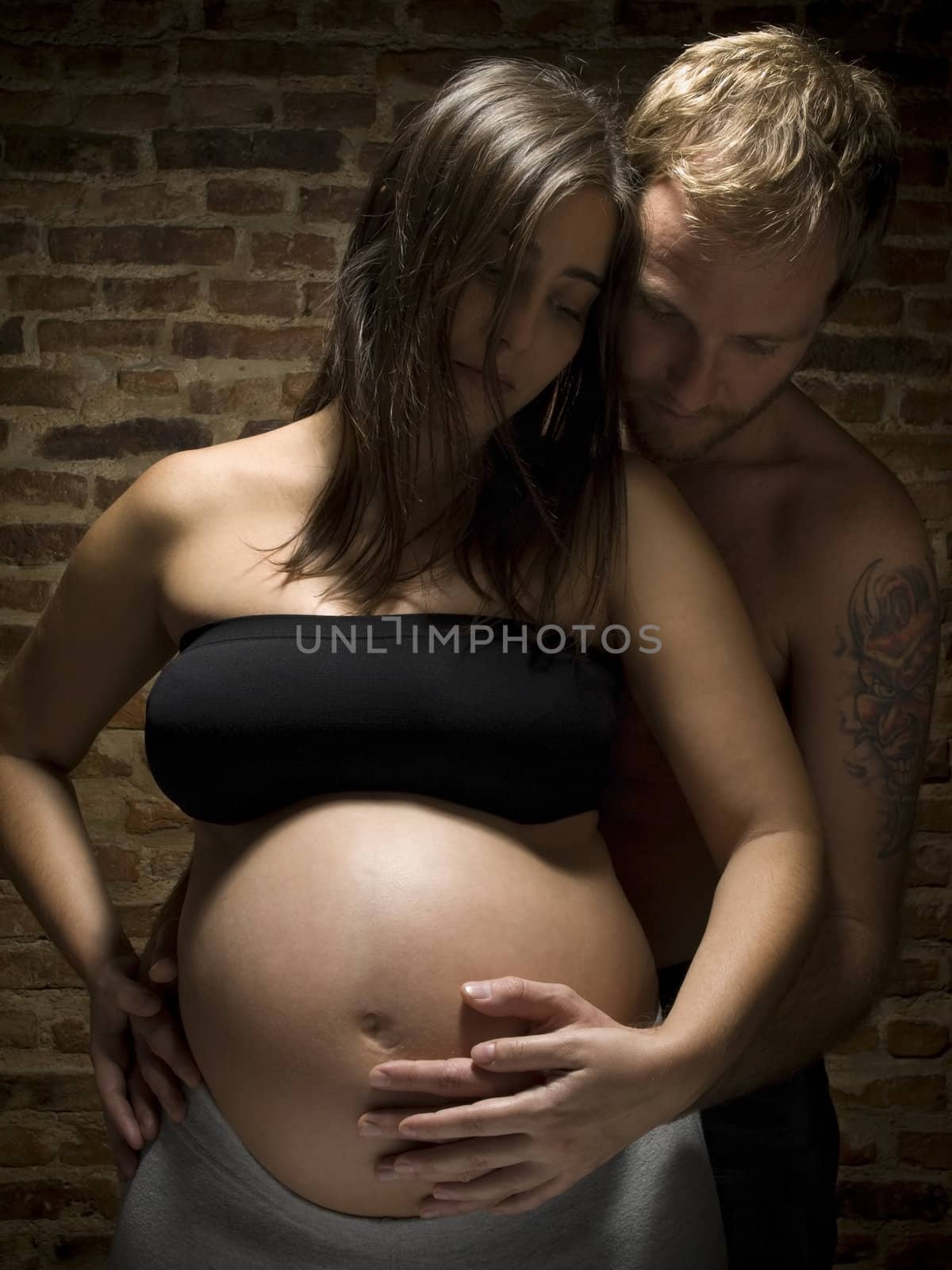 A man holding his pregnant wife's belly.