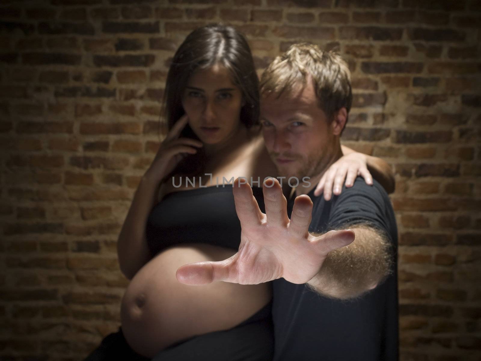 A man try to stop the picture to be taken.Woman on her eighth month of pregnancy. Focus on hand.