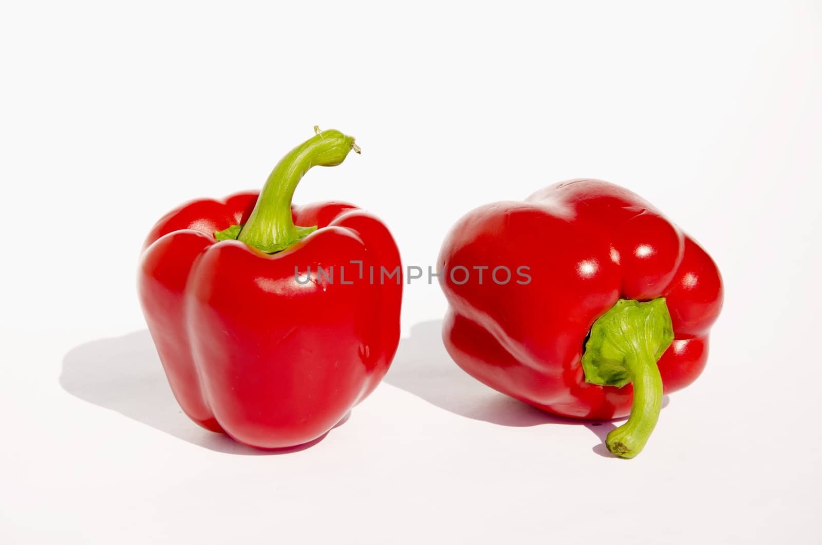 Two red papricas with green branches on a white background. Ecological and healthy food.