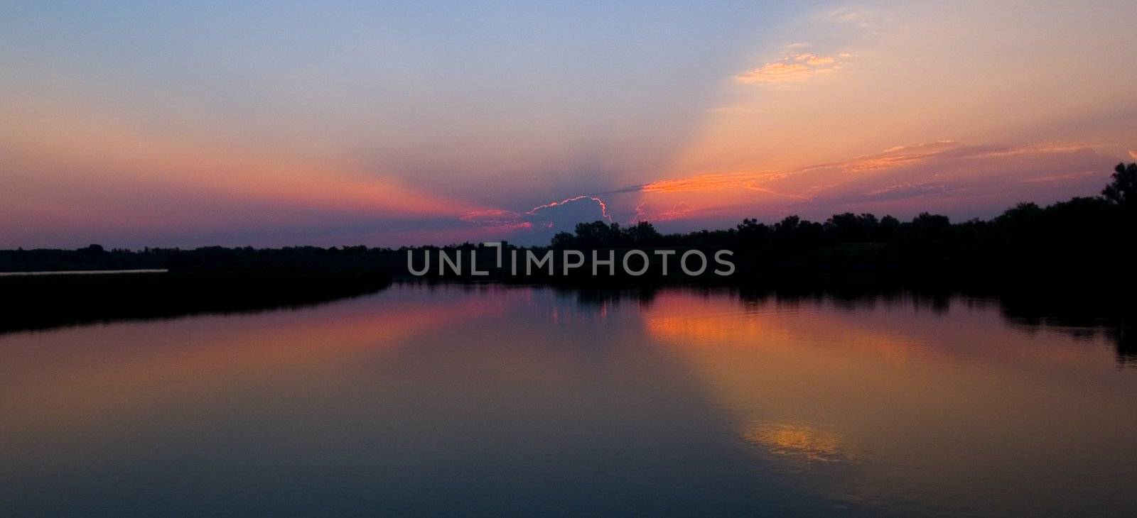 Dawn sunbeams emerge over lake Mitchell, South Dakota