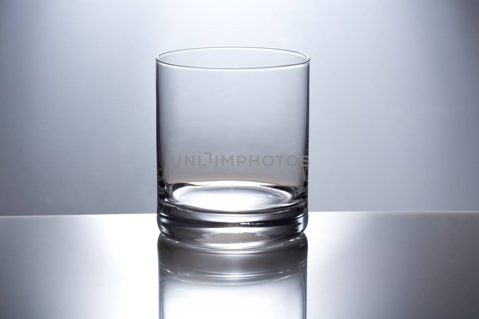 The empty transparent glass glass for whisky is reflected in a glass table
