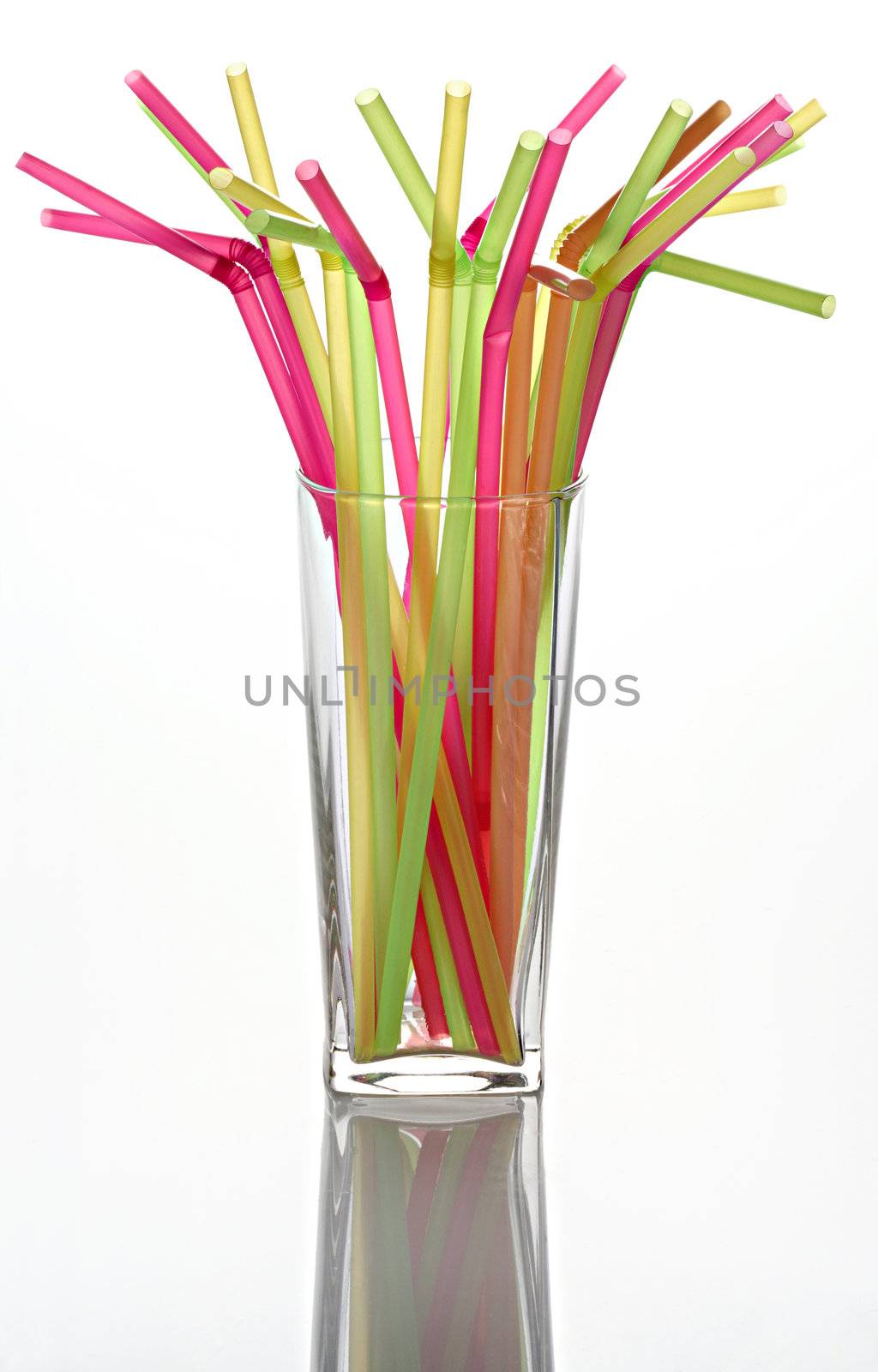 Multi-coloured straws for a cocktail in a transparent glass
