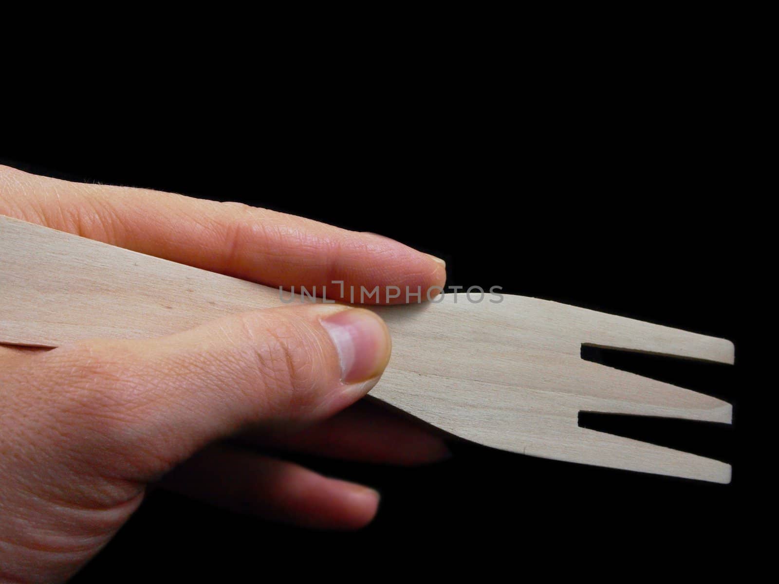 Person holding a wooden spatula, isolated towards black background