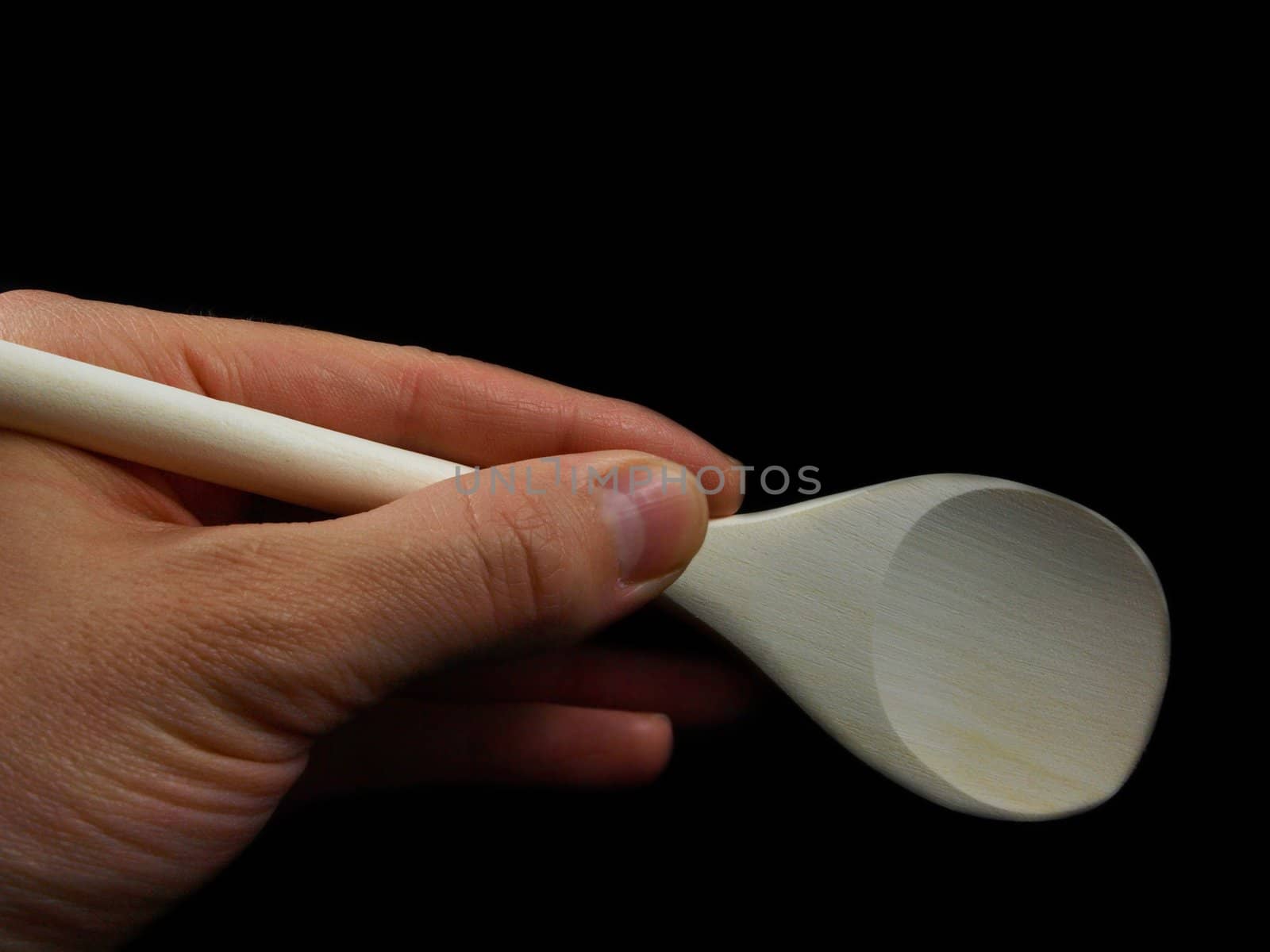 Person holding a wooden spatula, isolated towards black background