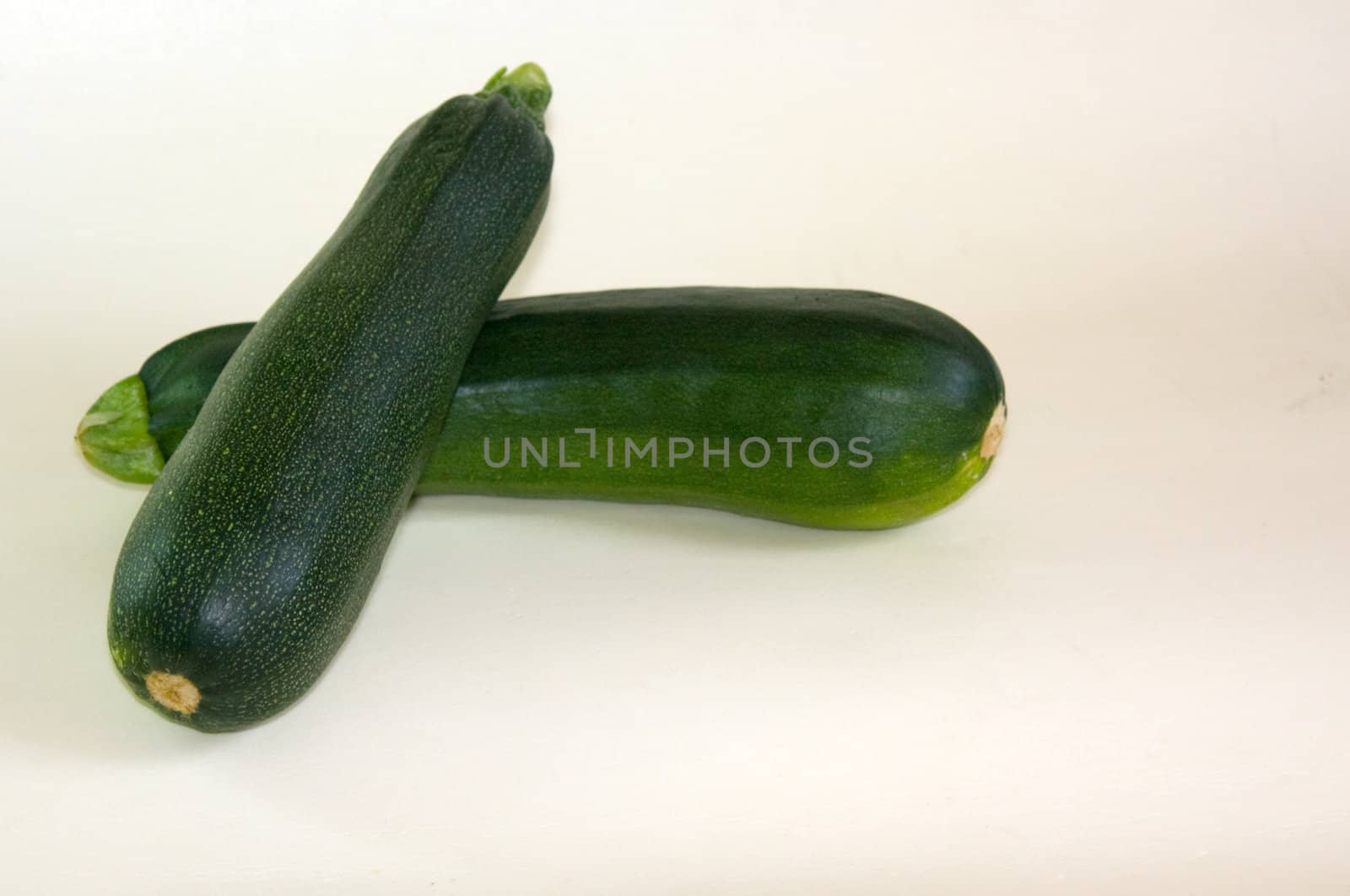 Two green vegetable marrows on a white background