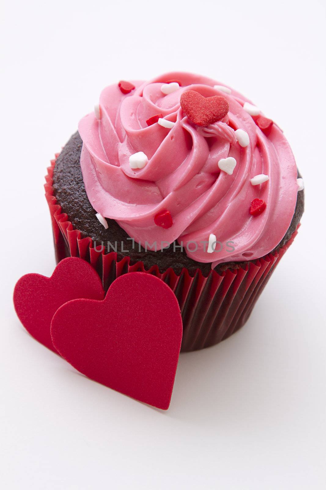 Chocolate cupcake decorated with pink frosting and candy hearts