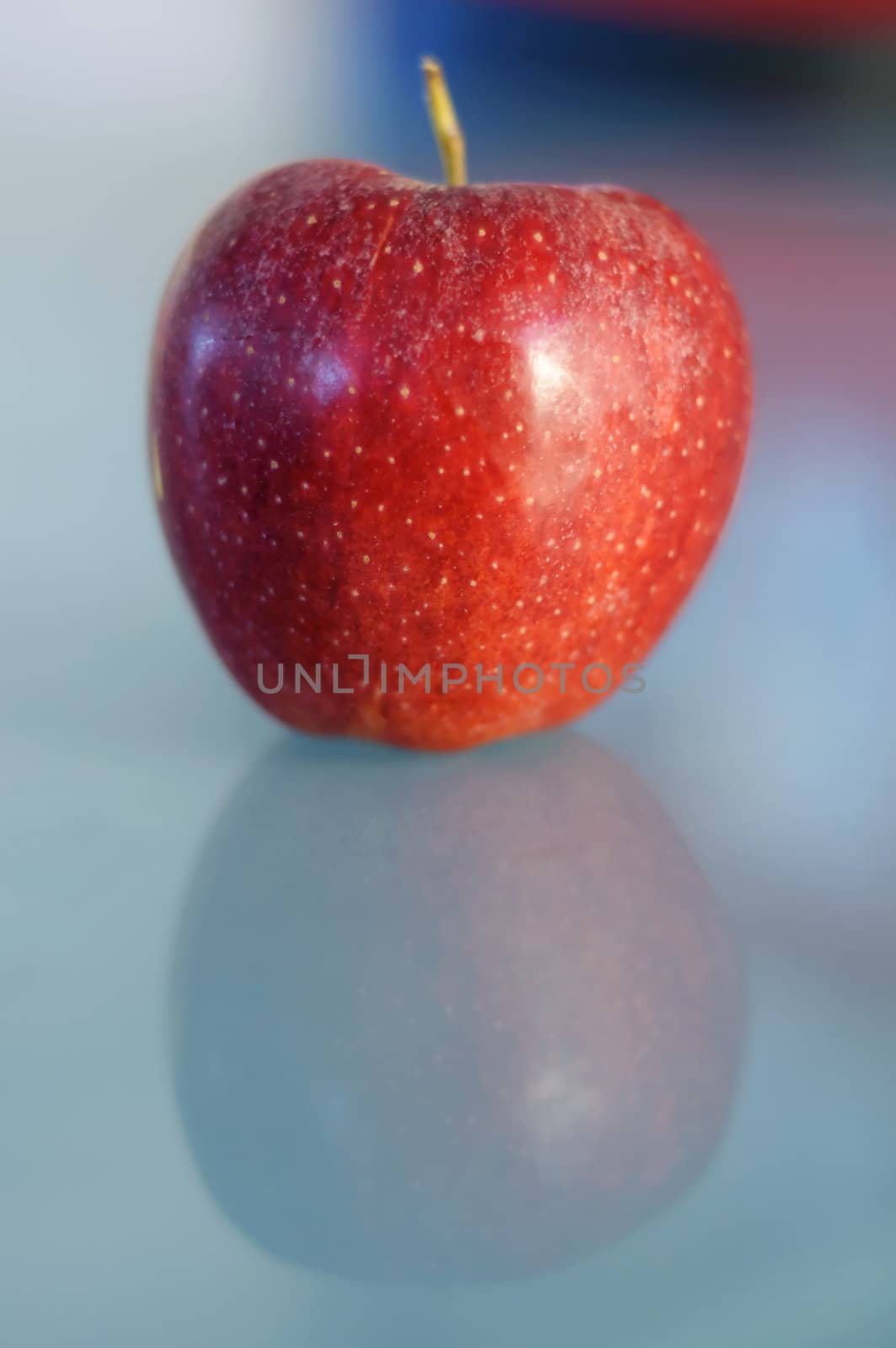 Red apple with its reflection on a table made of glass