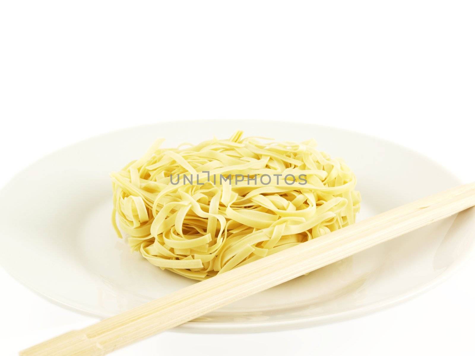 Dried uncoocked noodles, on white plate with chopsticks, isolated towards white background