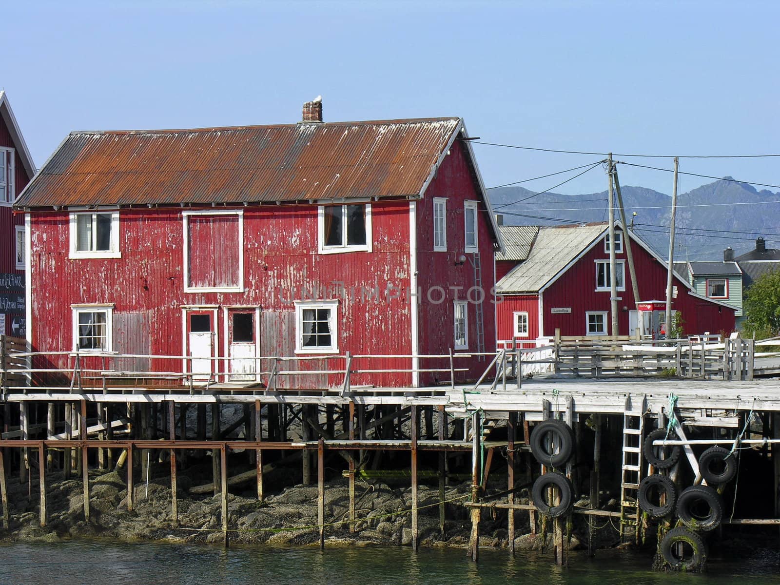 Old ruined red and white wooden nordic house over a river in Norway