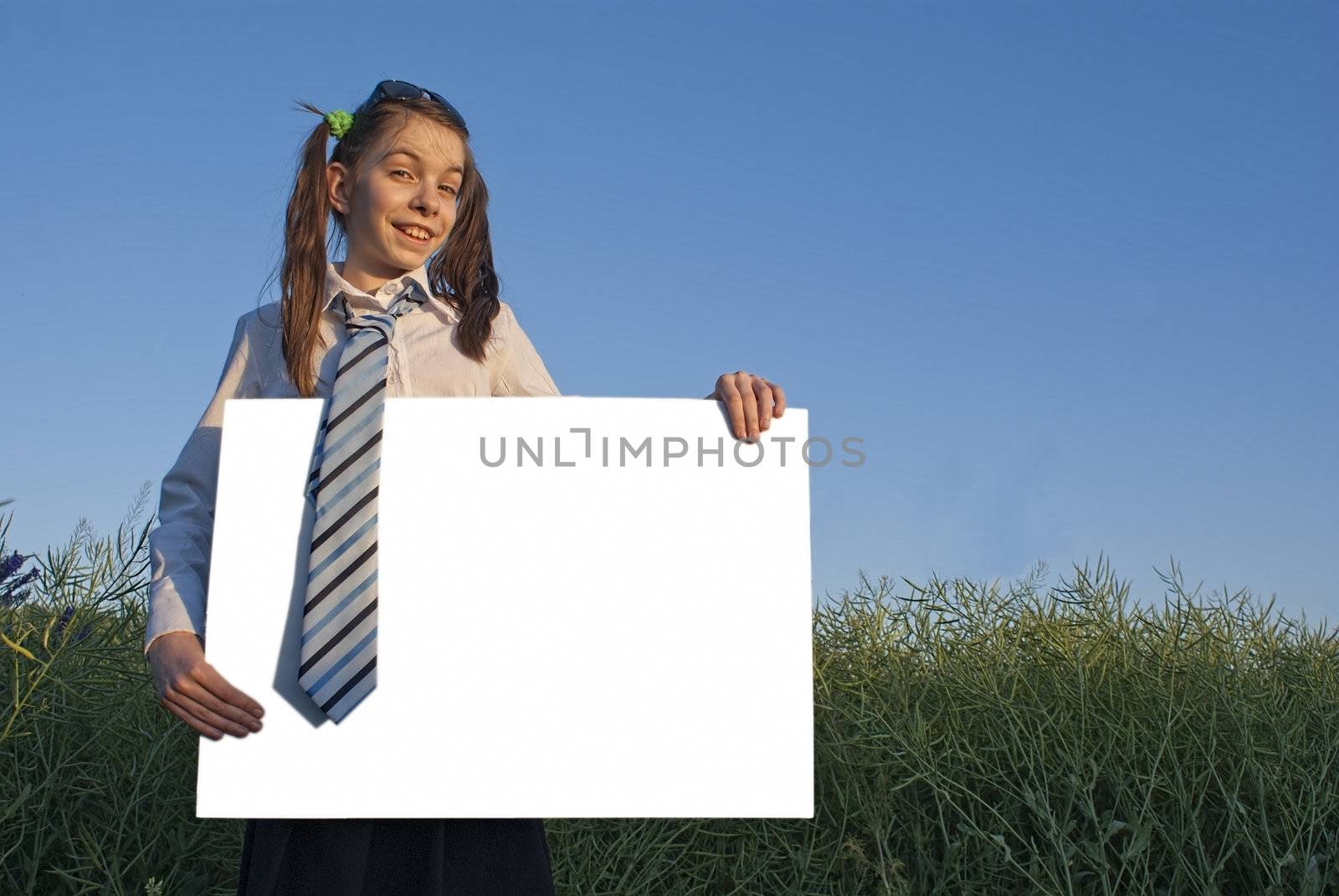 Teen girl holding white poster at green field