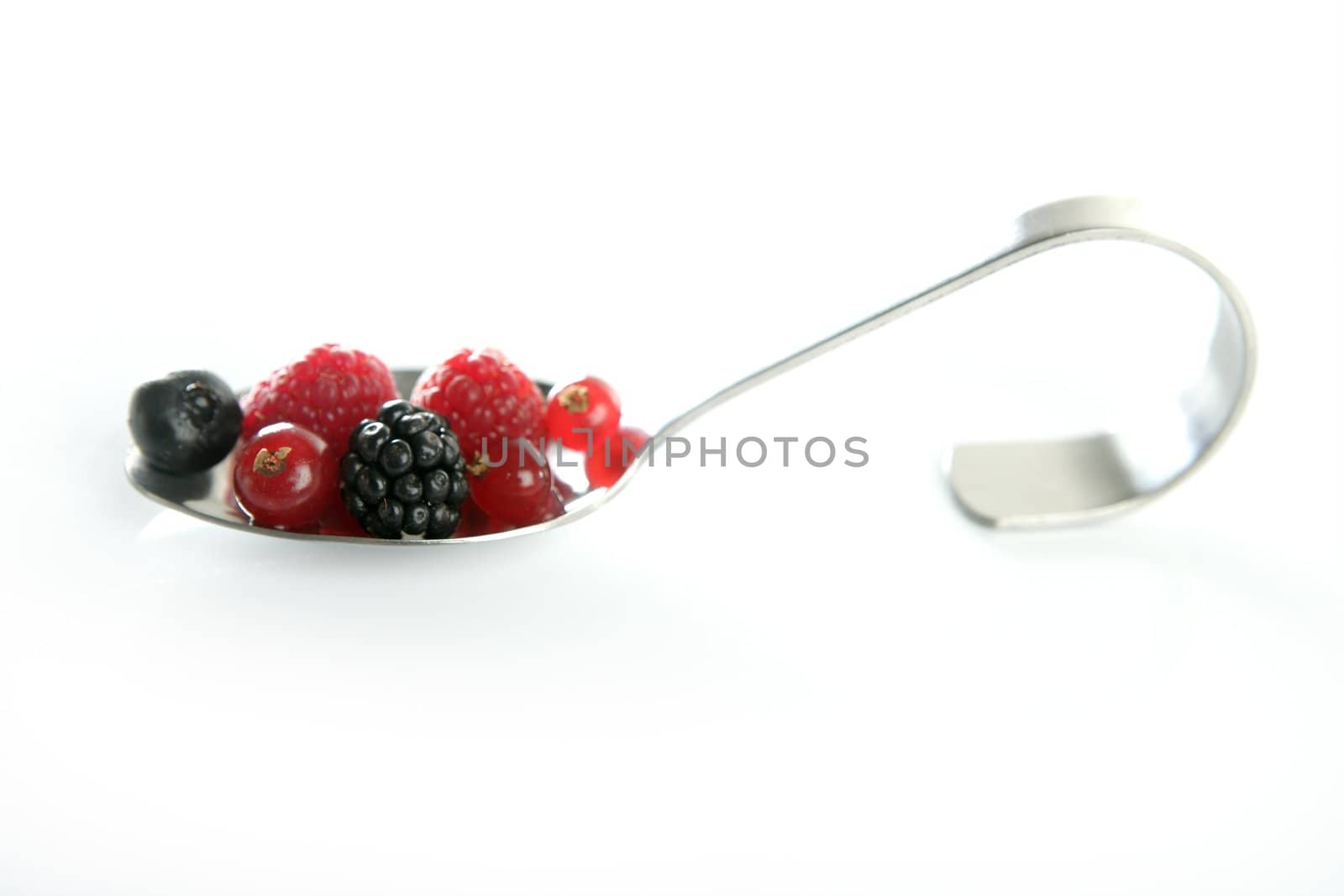 Varied berries in a curved spoon in white background