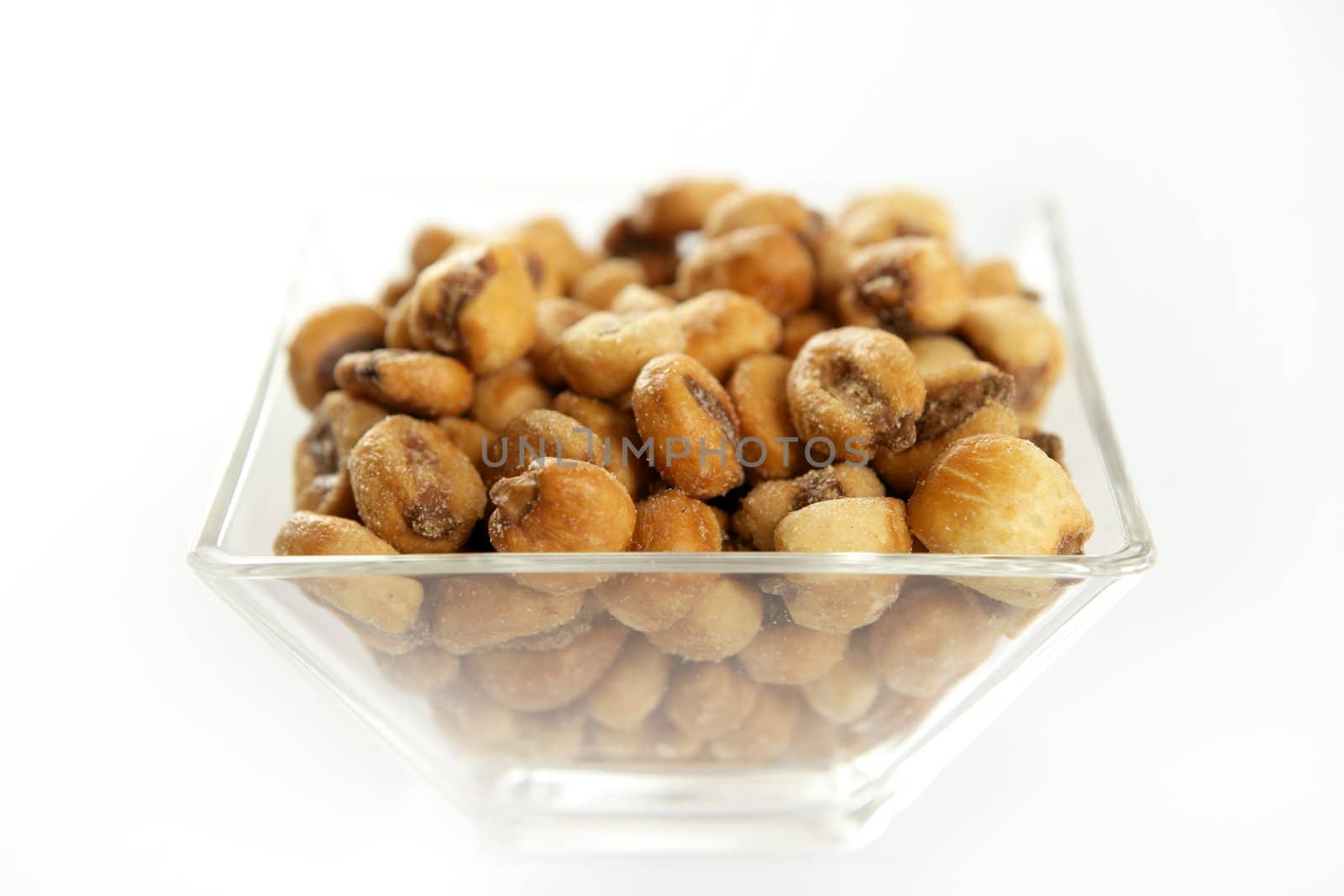 Roastwed salted corn in a transparent glass bowl, white background studio shoot