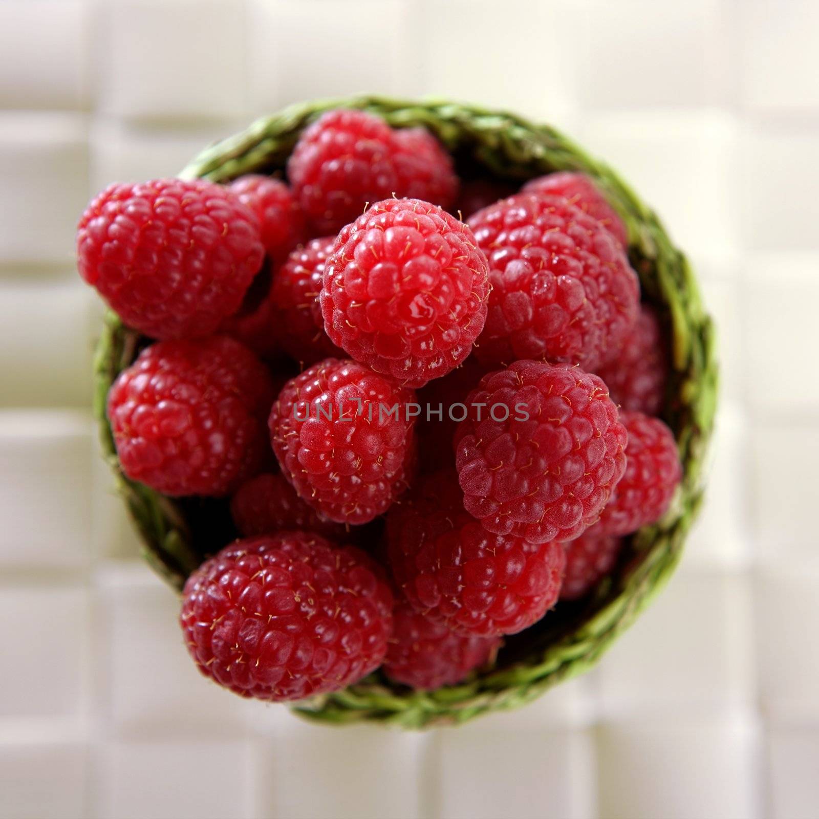 A group of fresh raspberries in a green little basket