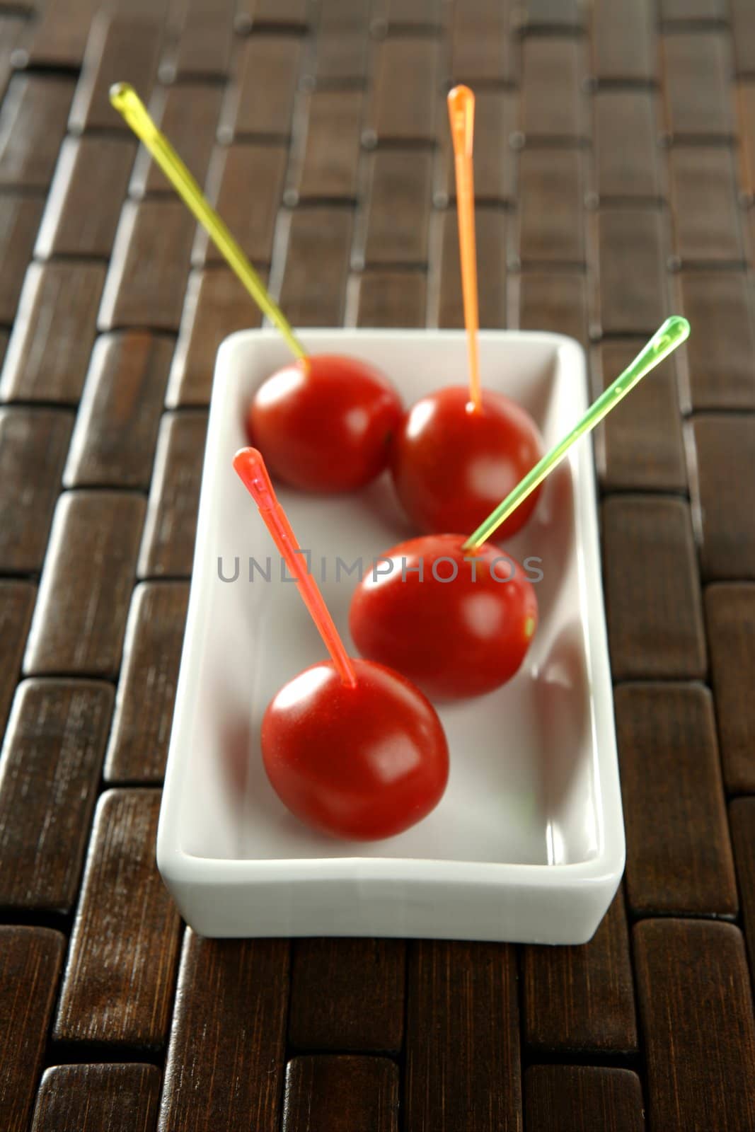 Tomatoes snack in a white dish and colored sticks