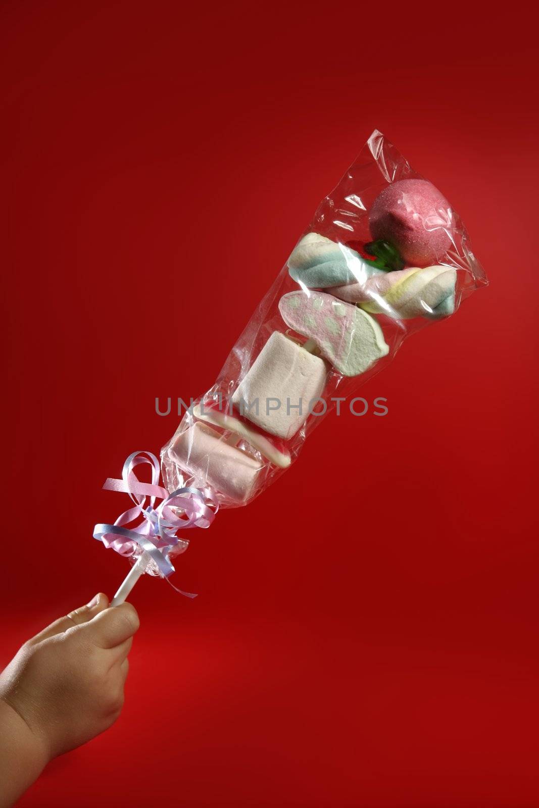 Candy colorful lolipop on child hand over red background