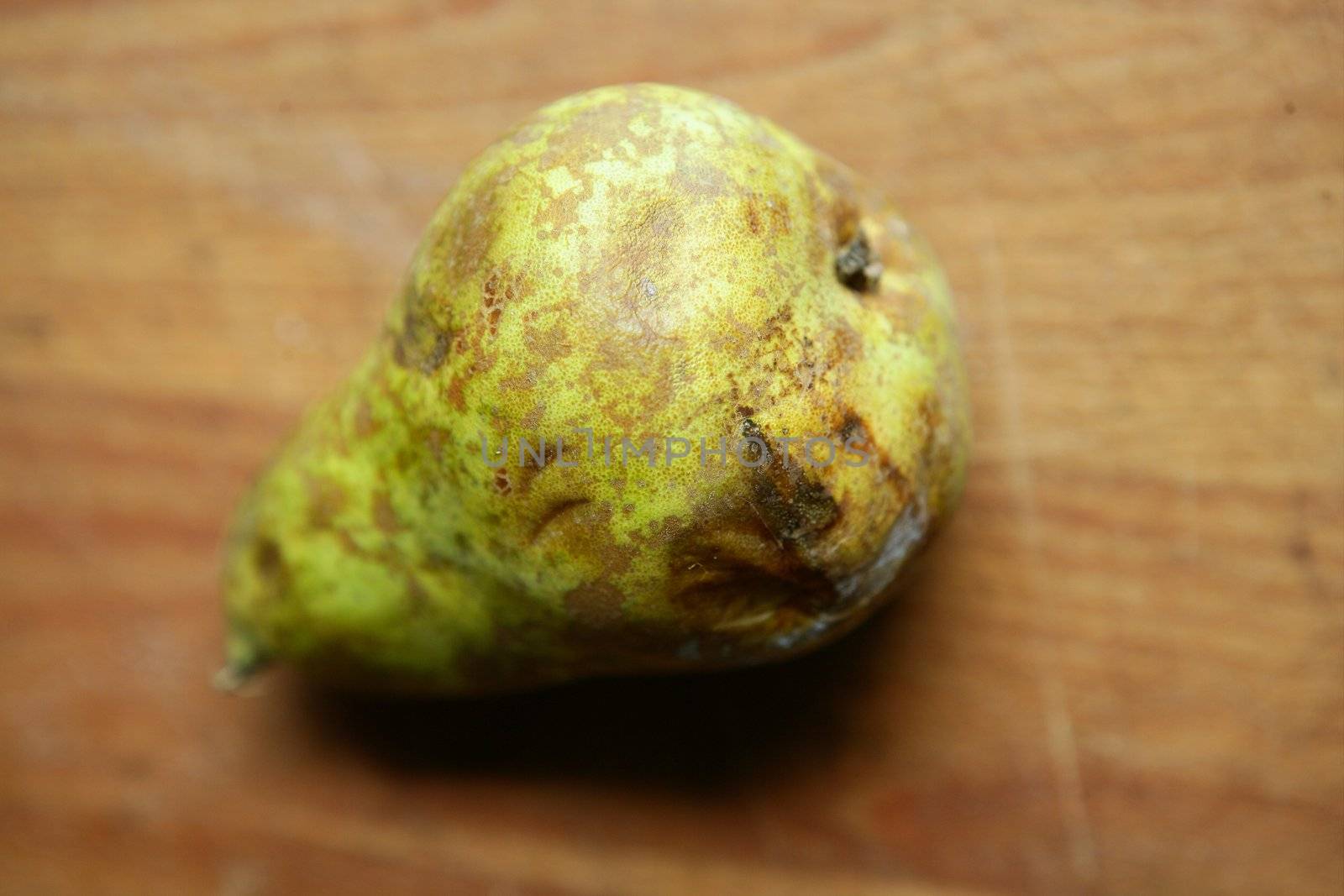 Rot green pear over warm wood table