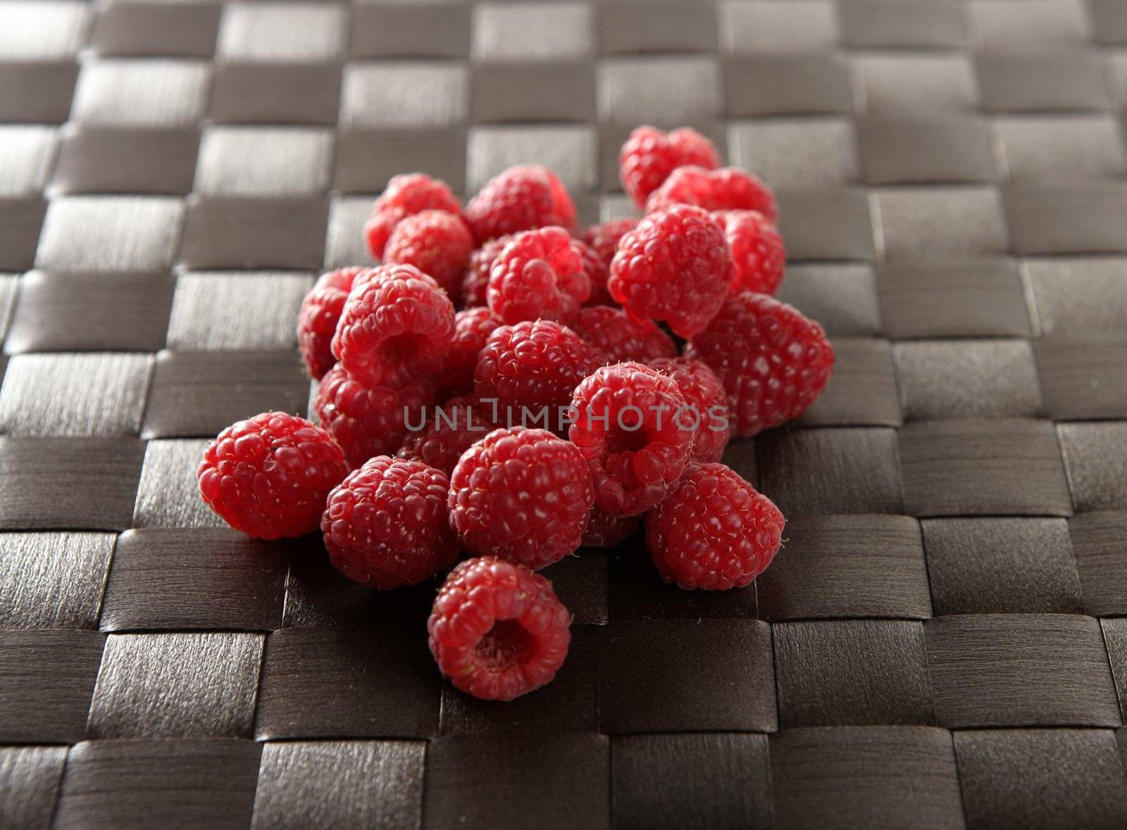 A group of fresh raspberries over brown tablecloth