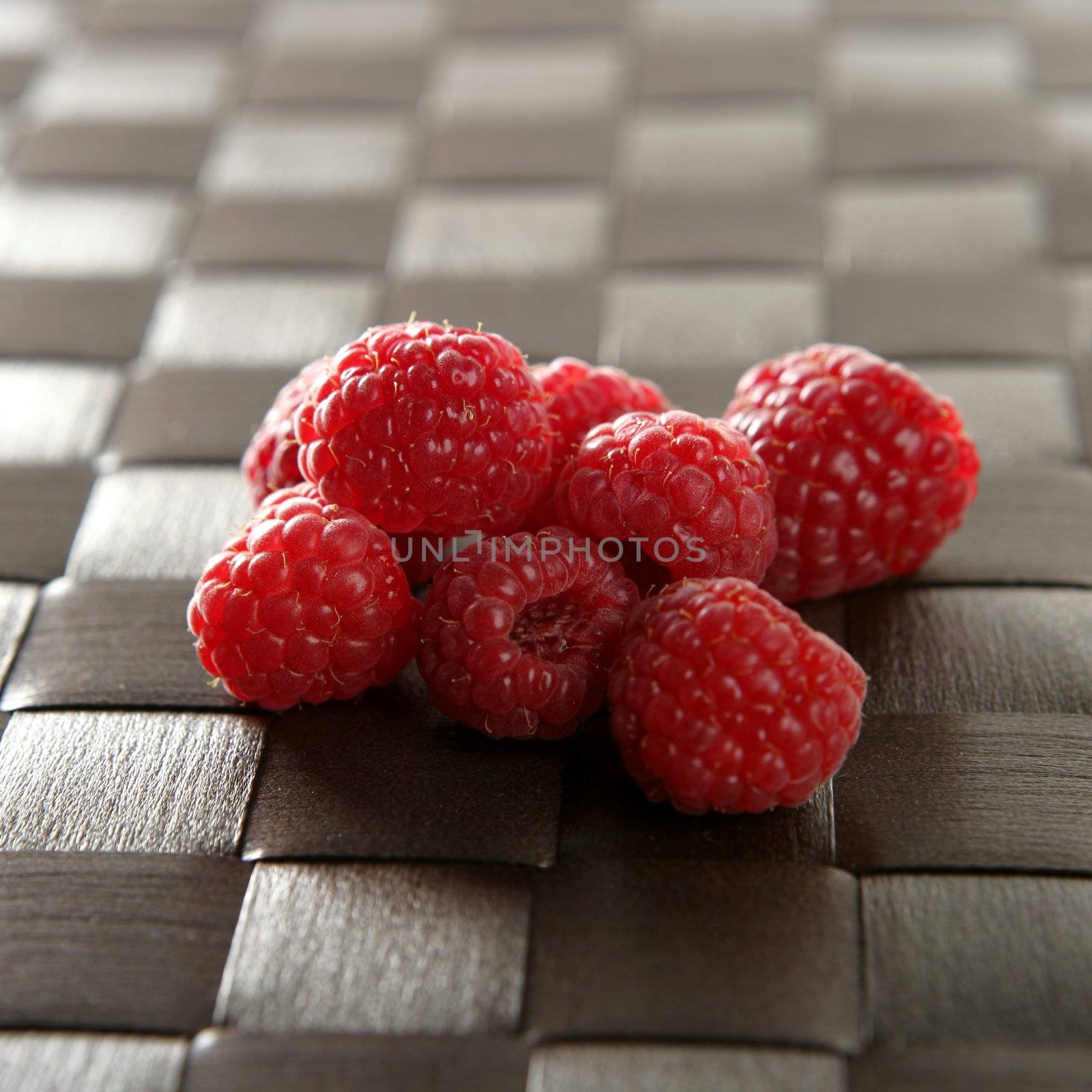 A group of fresh raspberries over brown tablecloth