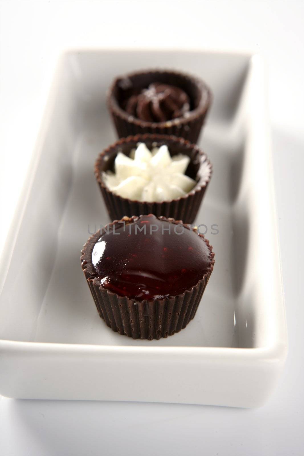 Three little chocolate cakes in a line by lunamarina