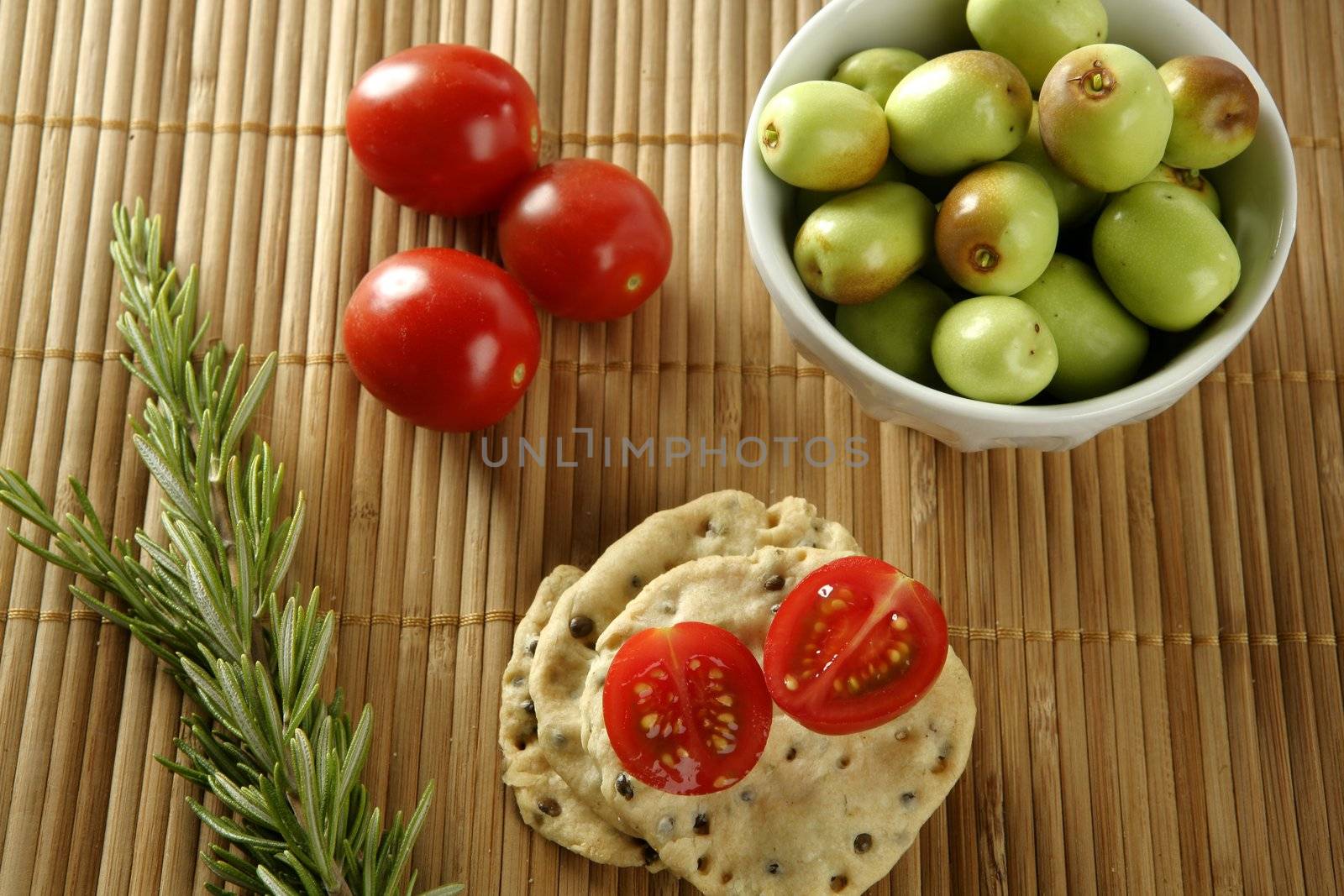 Sesame seeds biscuits over bamboo stripes, tomatoes ans rosemery