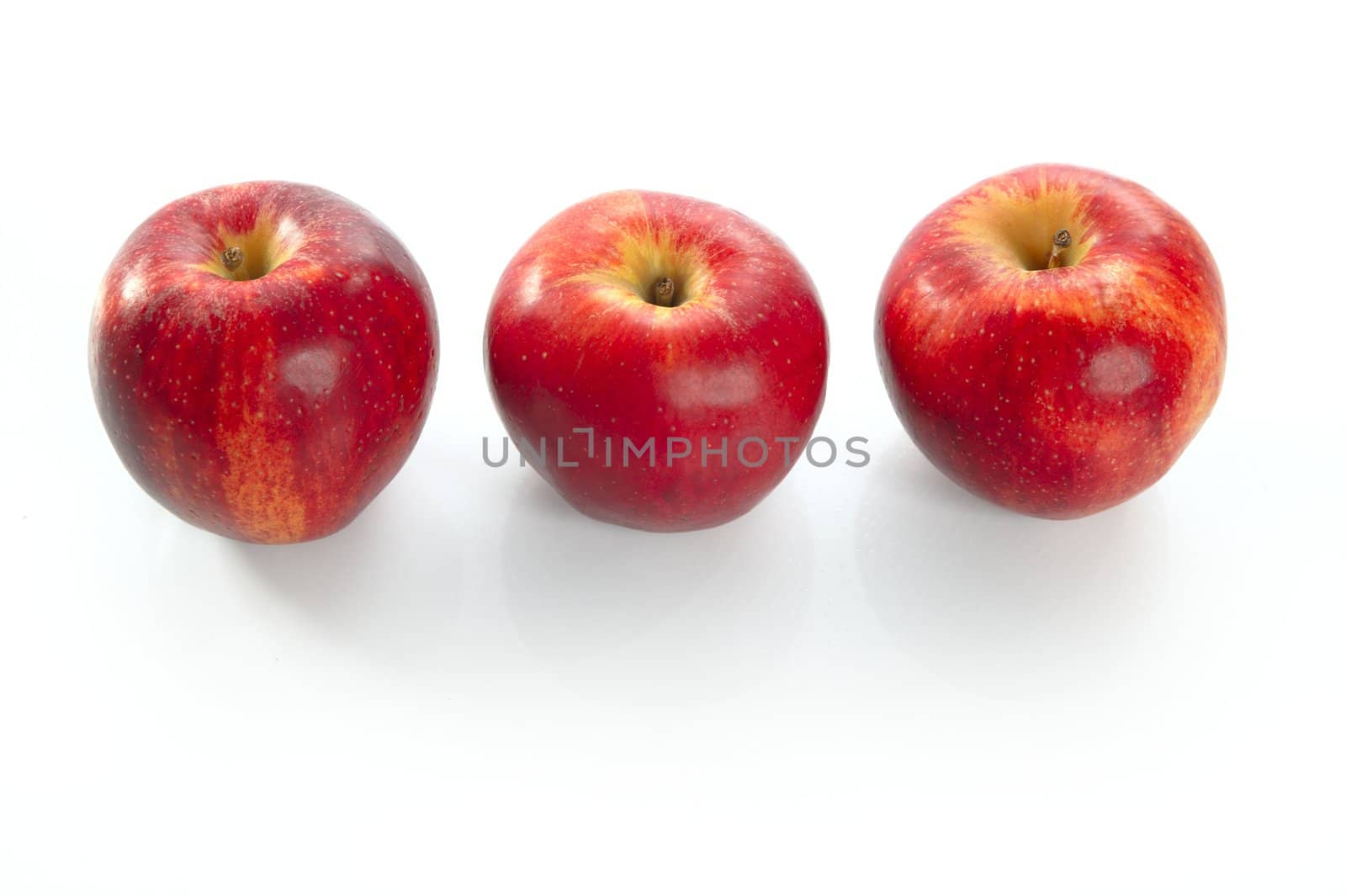 Three red apples in a row over white background