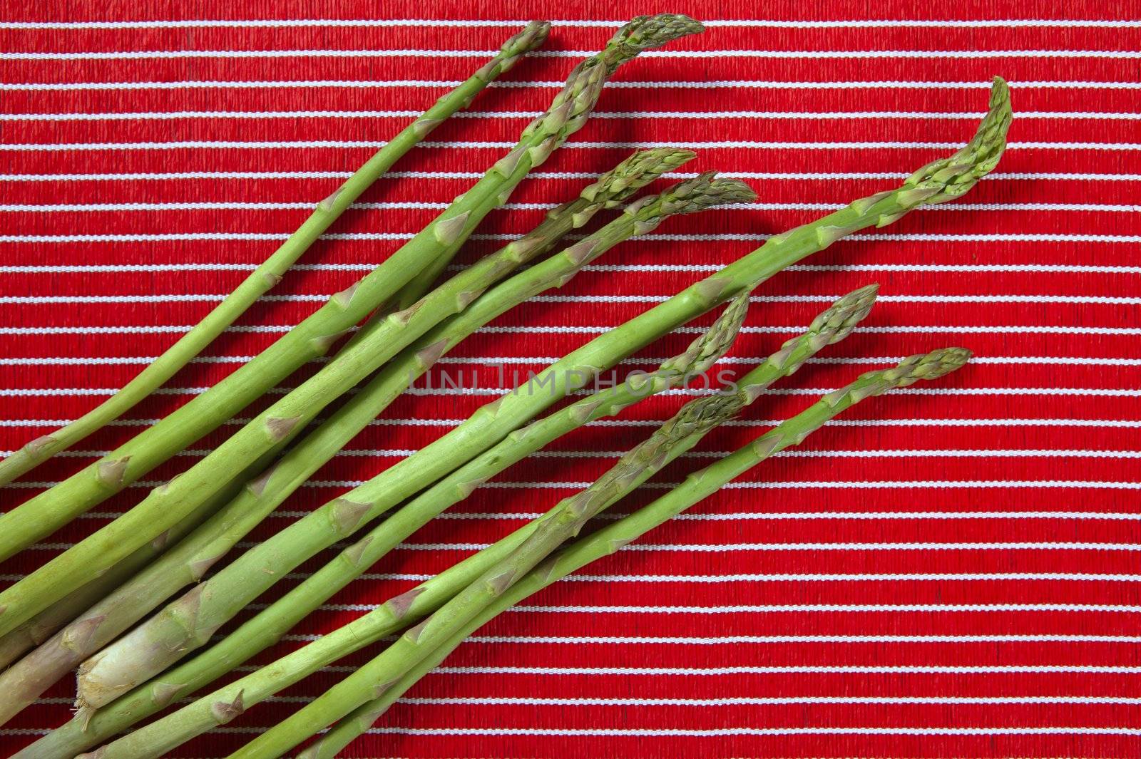 Green asparagus over red tablecloth background