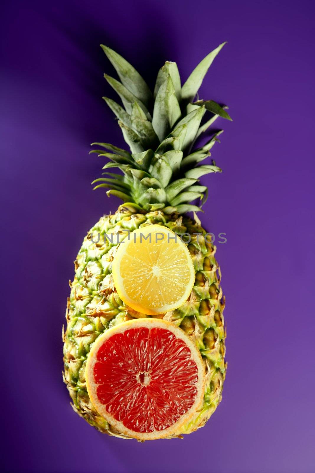 lemon slices over pineapple on purple background
