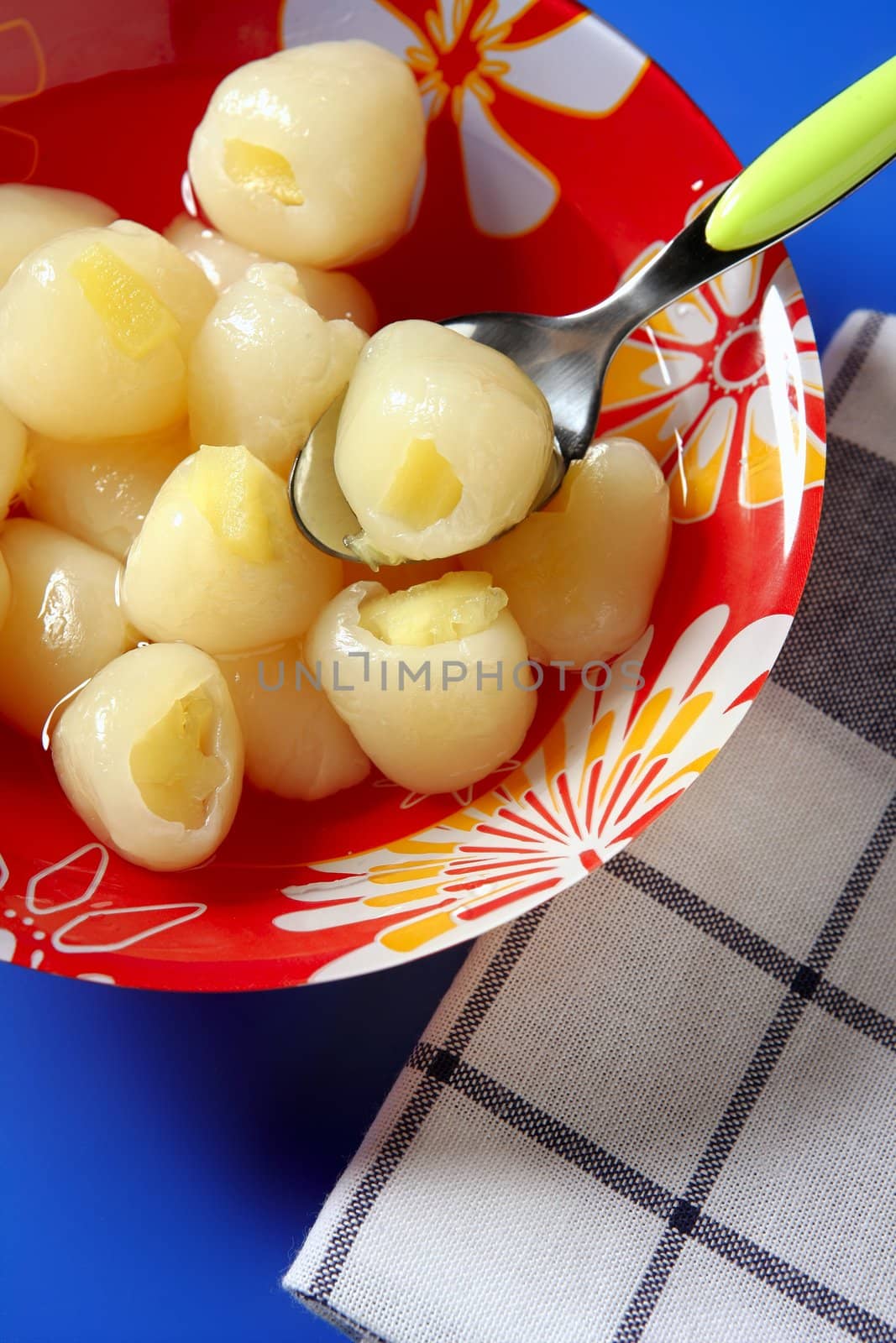 Rambutan, lychee with pineapple inside dessert, over blue