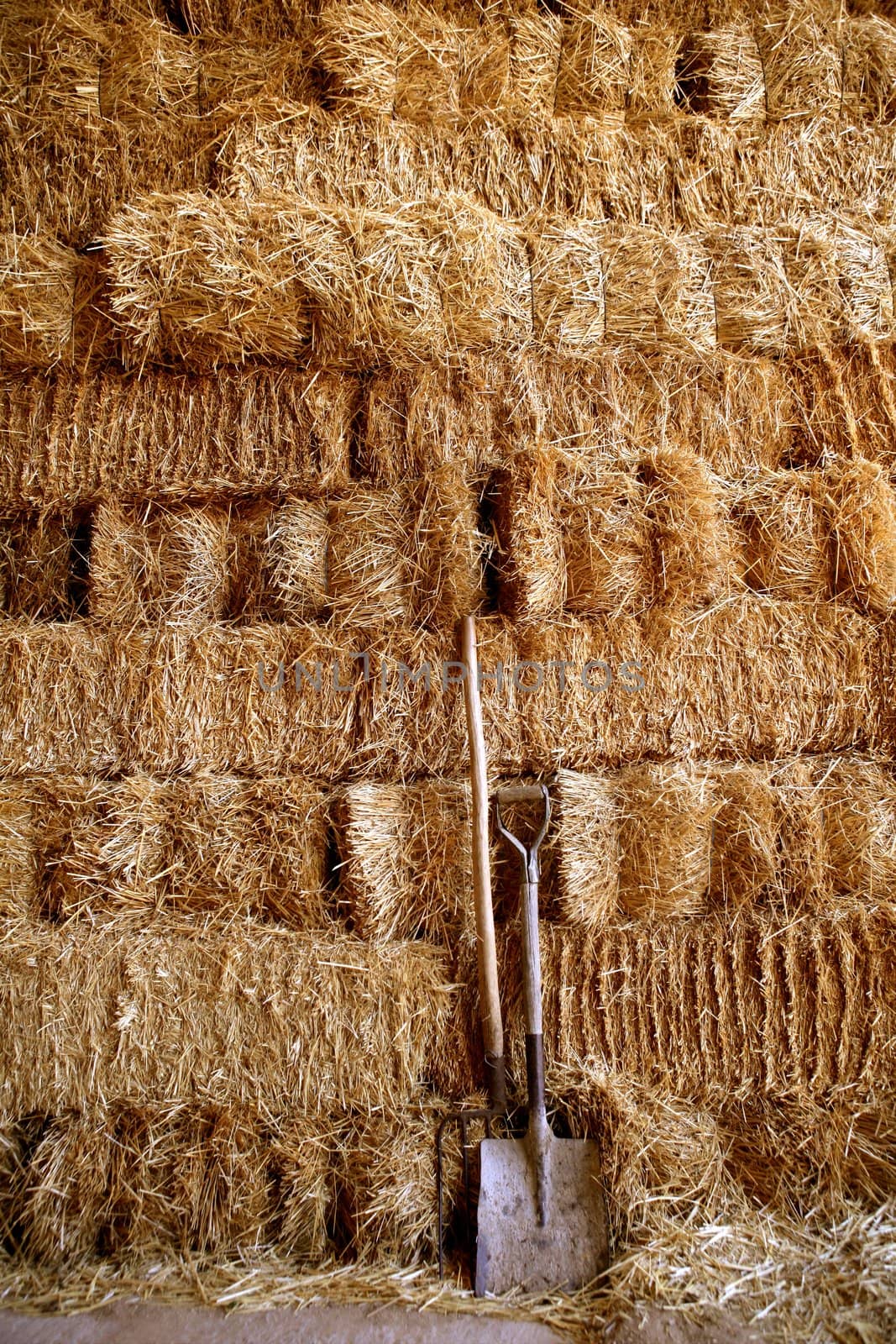 Straw golden bale barn stacked, shovel and rake tools