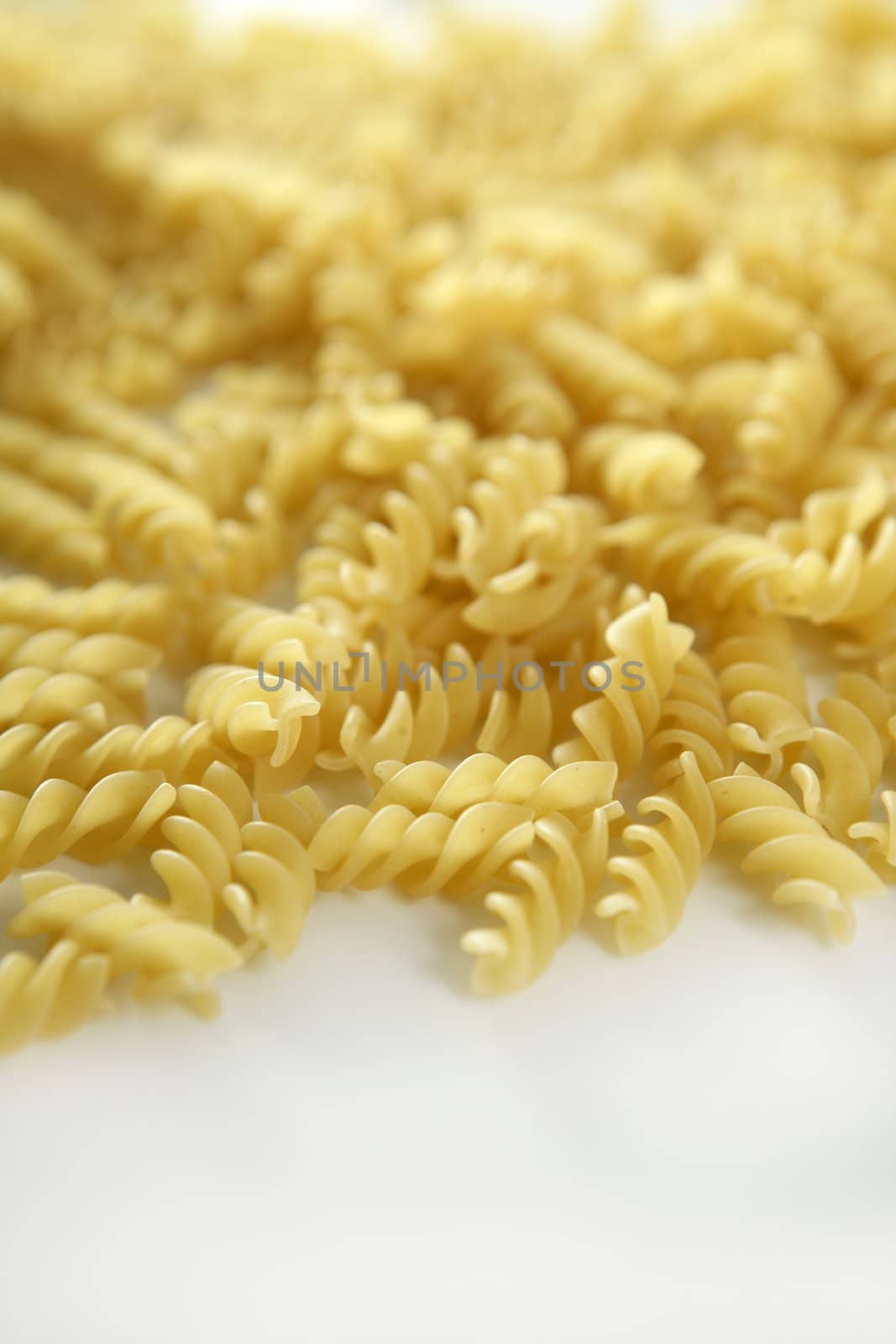 Italian spiral pasta texture with selective focus, white studio background