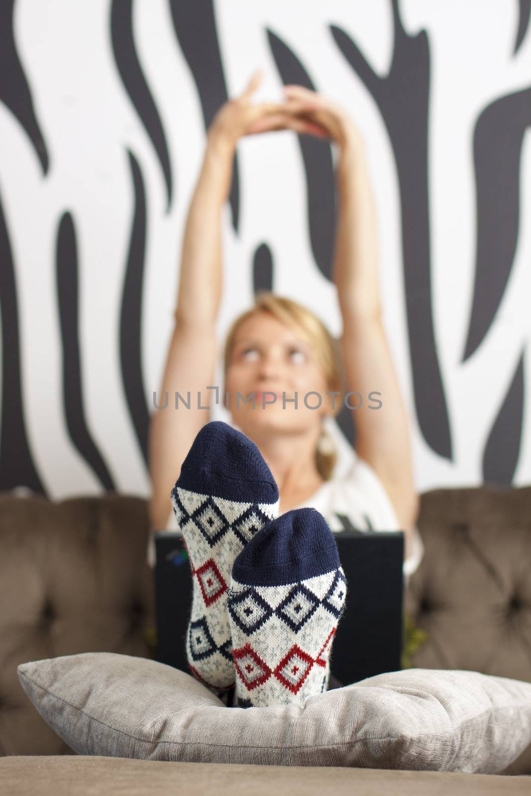 Relaxed, beautiful young woman sitting on sofa, using netbook