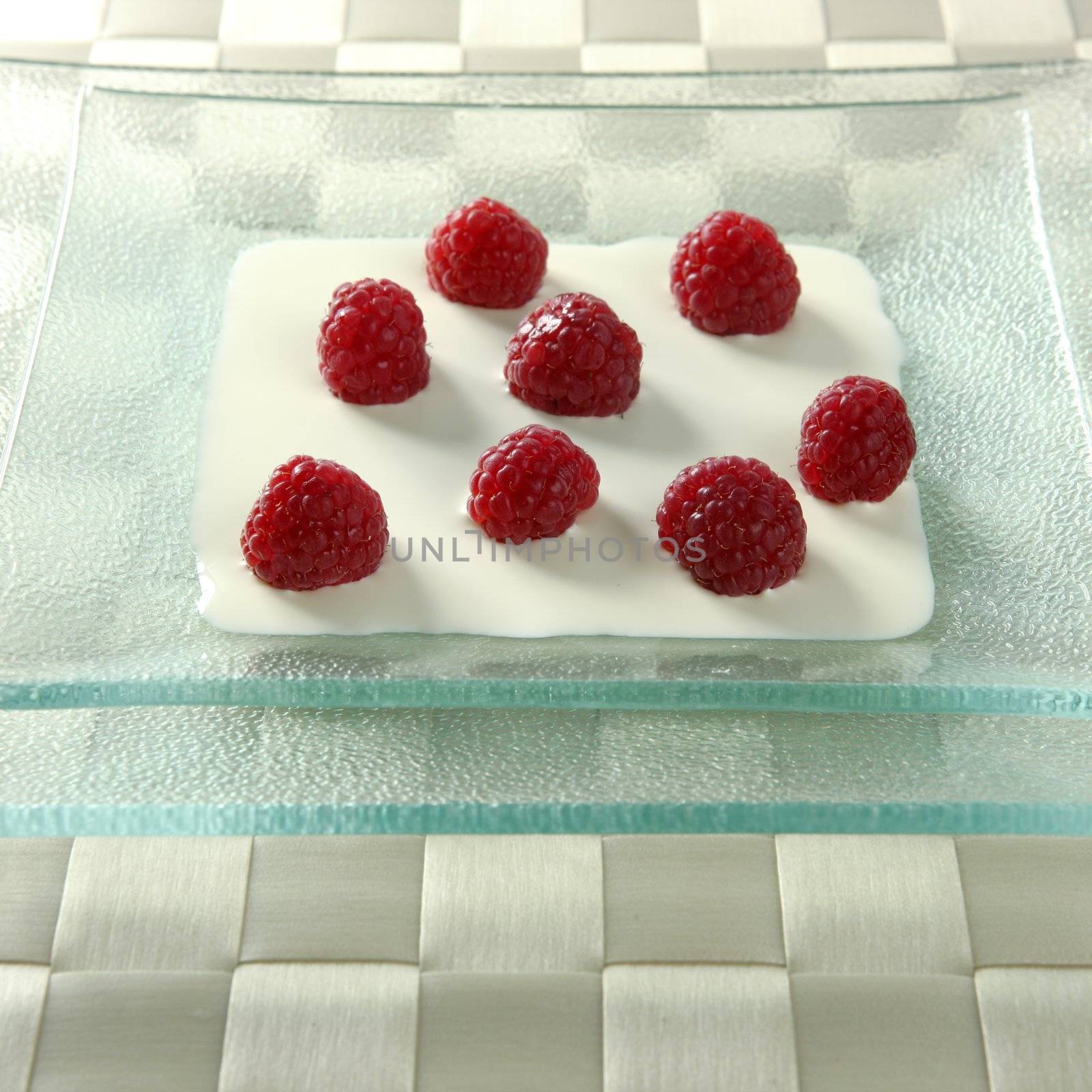 Dessert plate with cream and raspberries in square glass dish