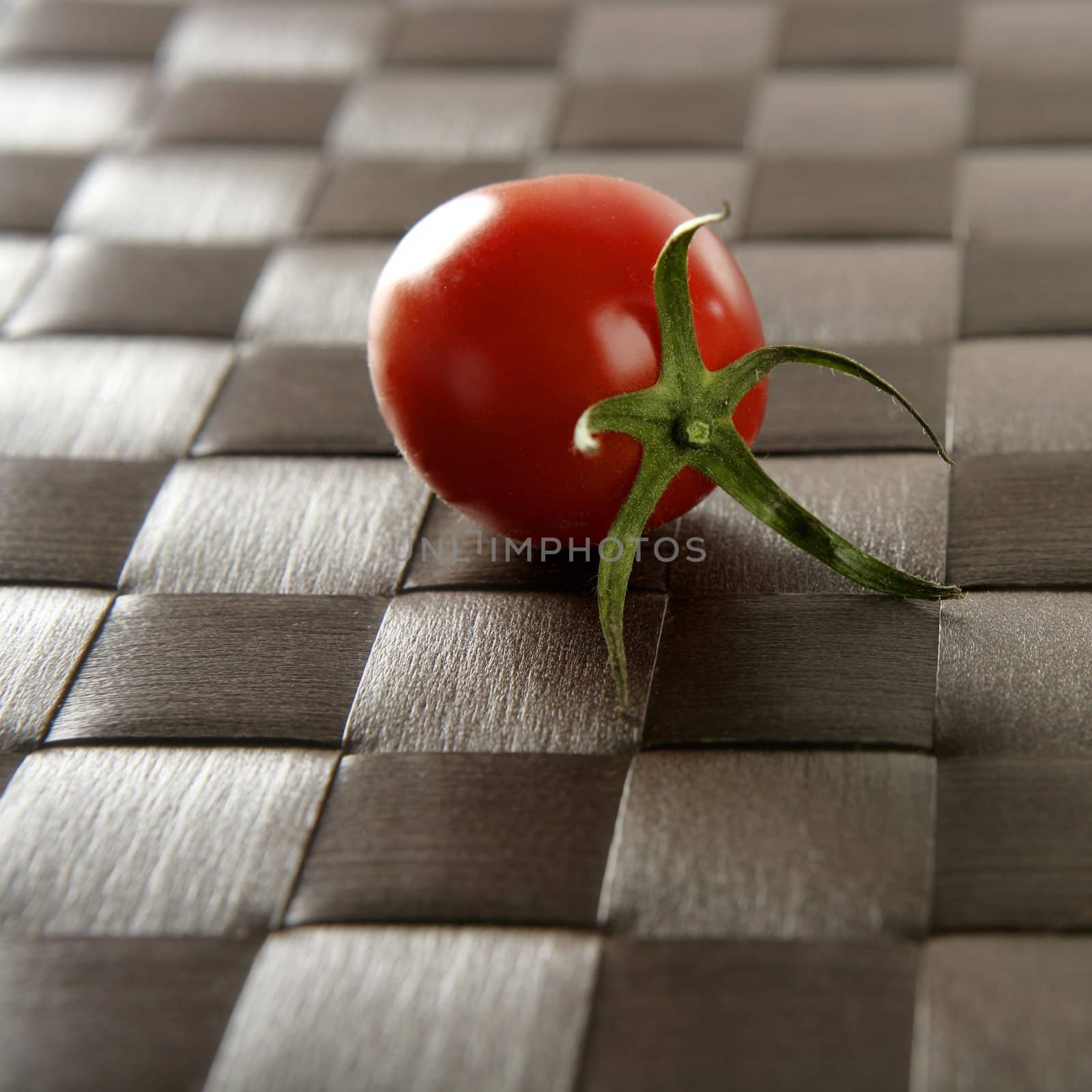 Close up of whole one cherry tomato over a brown tablecloth