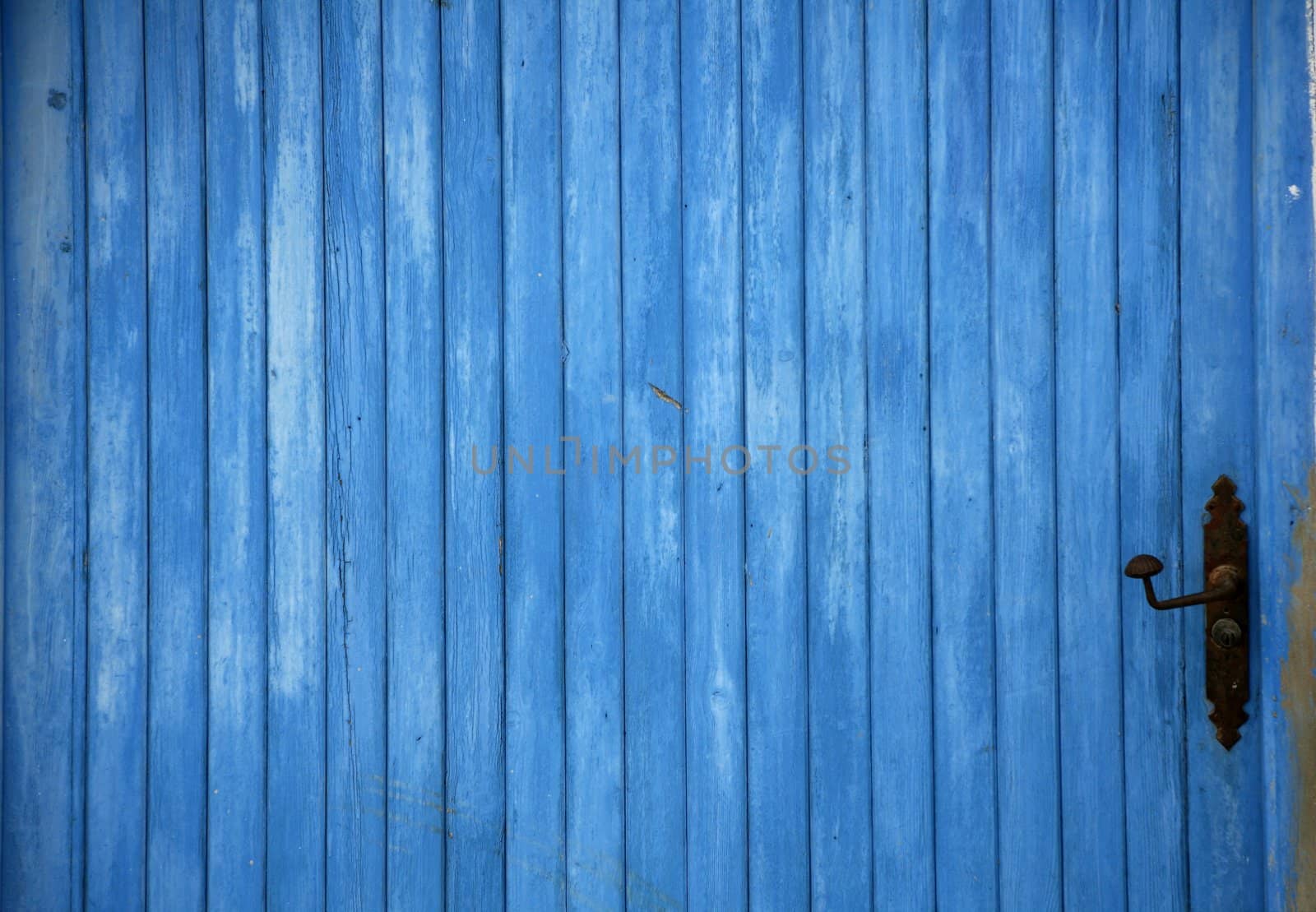 Blue old mediterranean wooden door detail with black handle