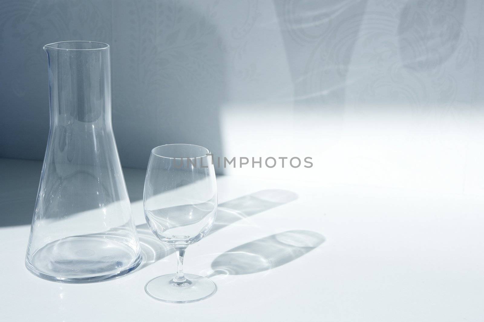 Water glass and bottle with transparent shadows in white kitchen