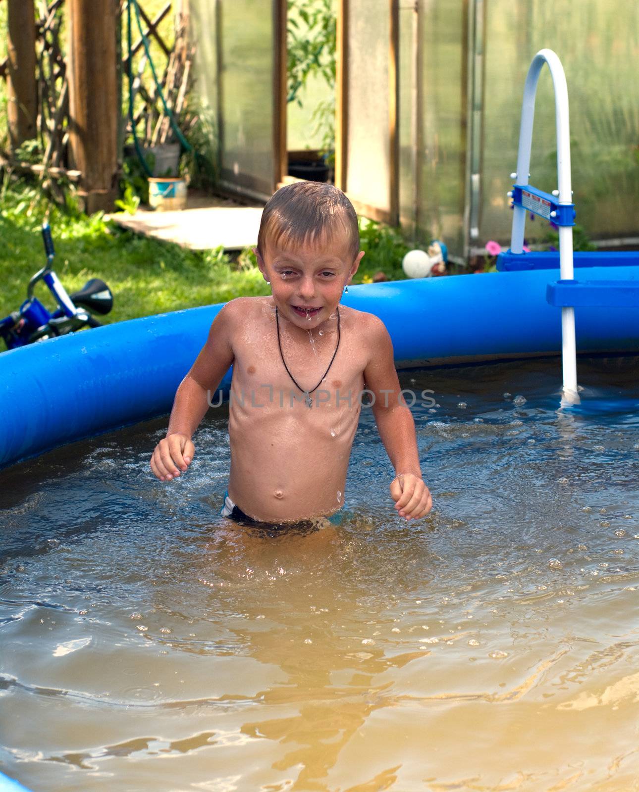 The boy bathes in dark blue inflatable pool