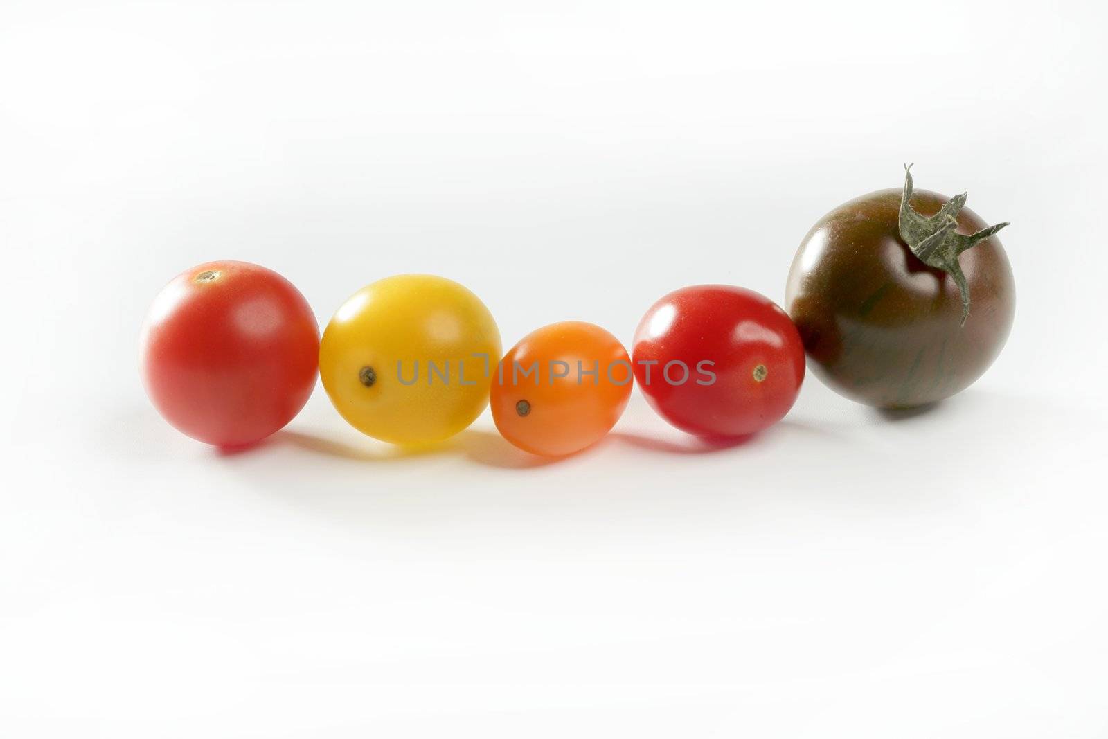 Little cherry varied multi color tomatoes, at studio, white background