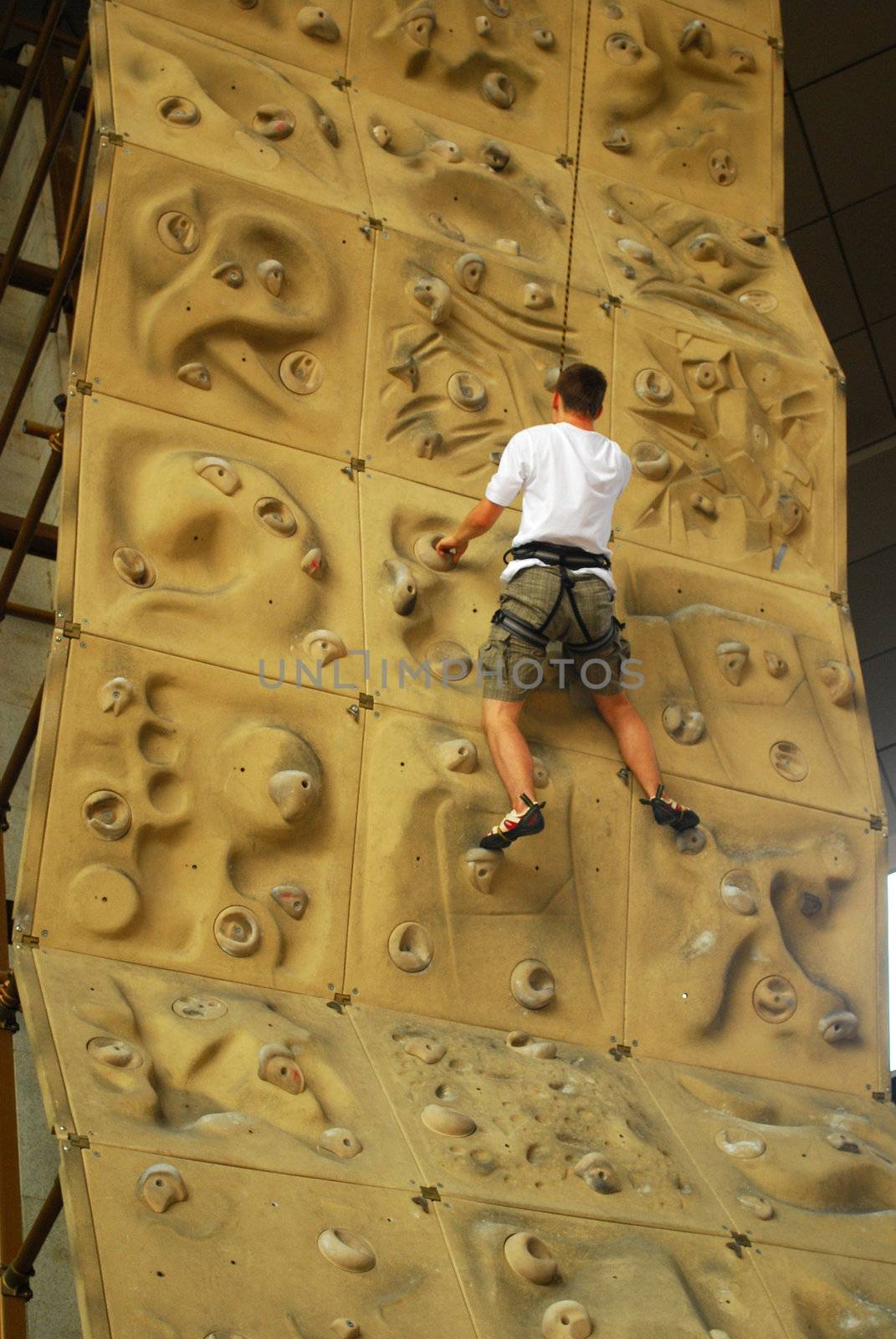 upward view of person climbing up a climbing wall
