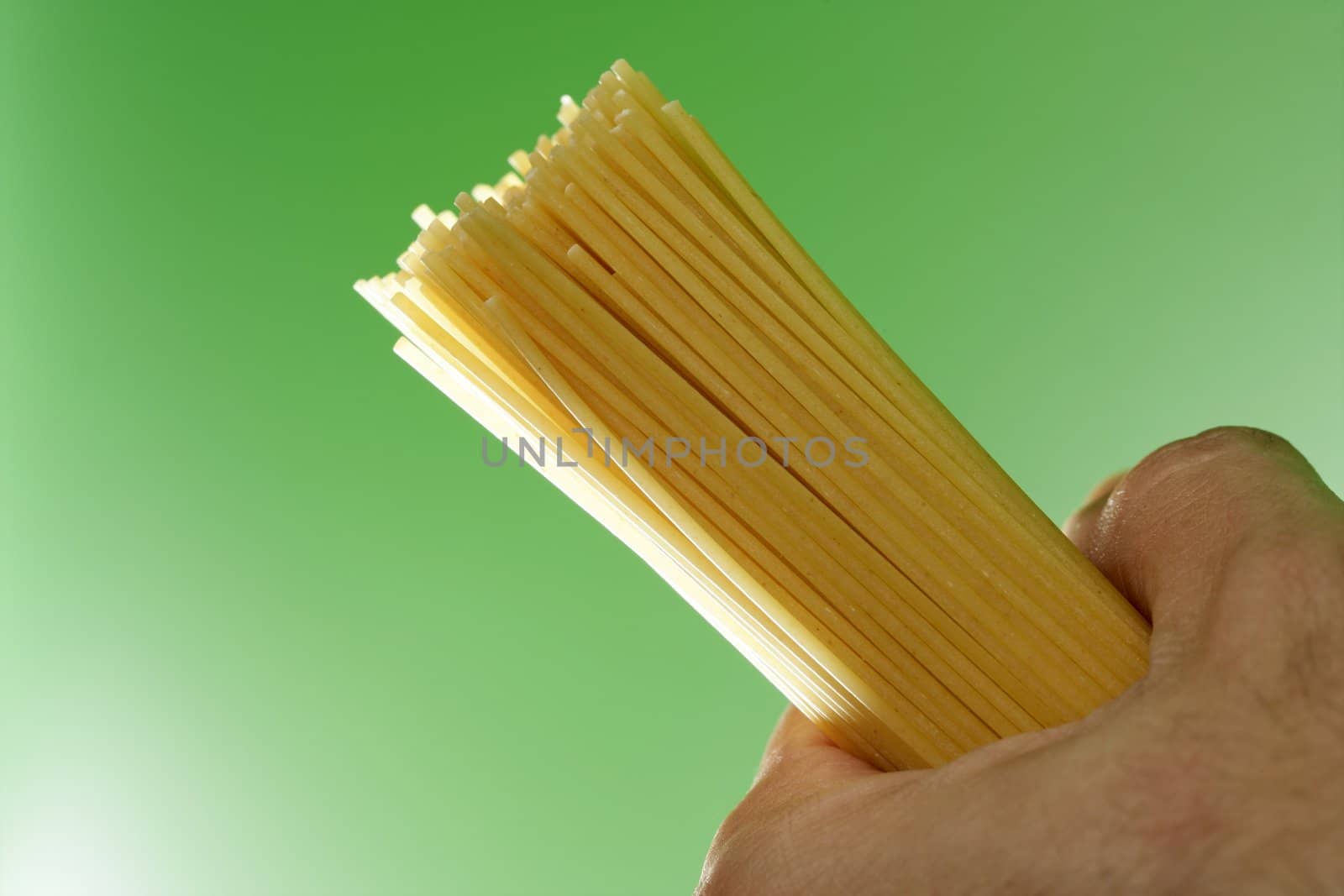 spaghetti in humand hand on green background at studio