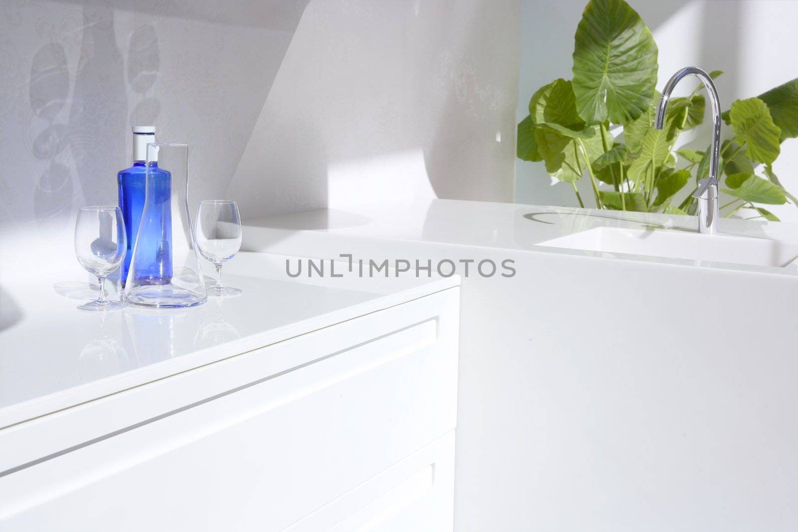 White modern kitchen detail, blue water bottle and green plants