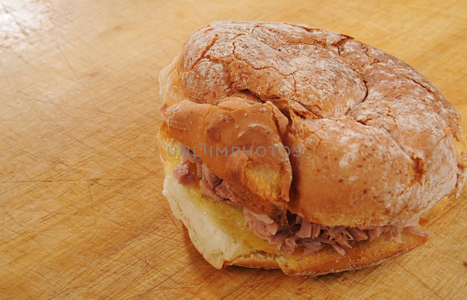 Tuna and Mayo in bread roll on a wooden table, shot against black.
