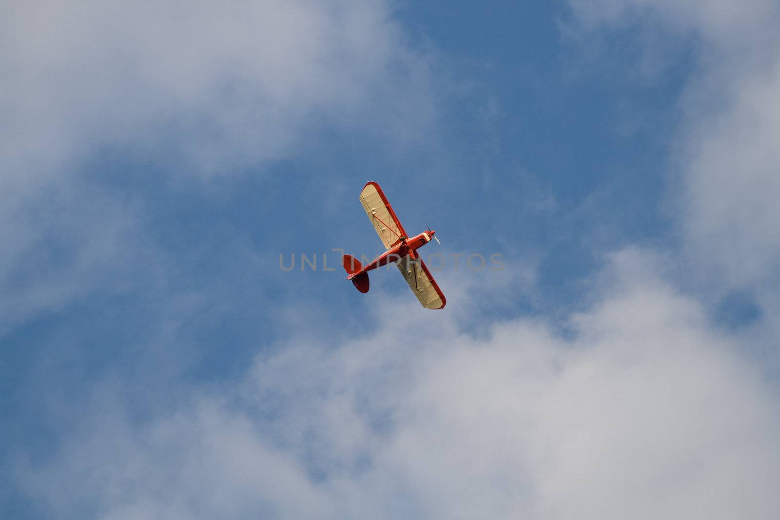 Flying small private airplane against blue cloudy sky