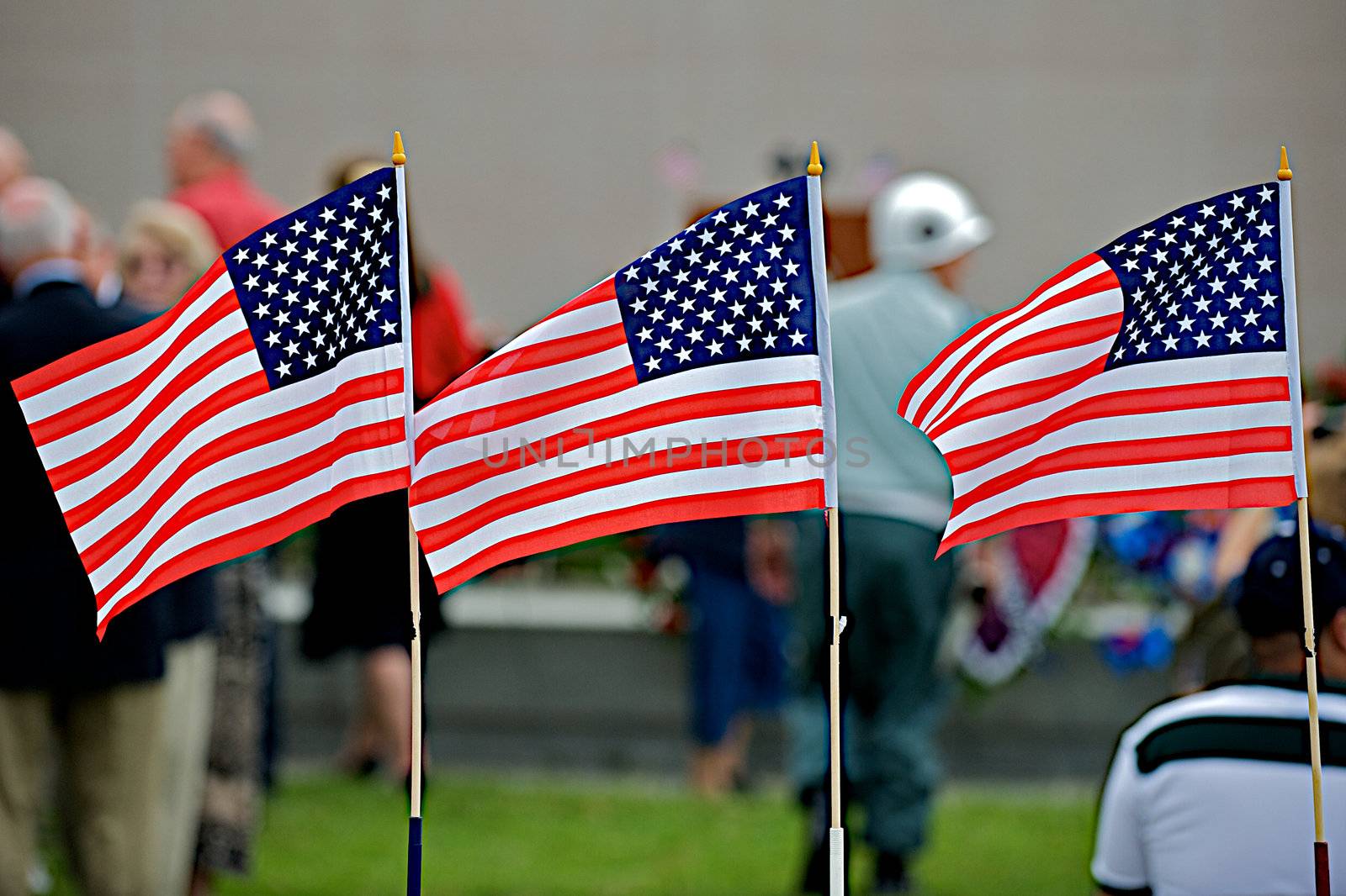 Three United States flags waving in the breeze during a Memorial Day event.