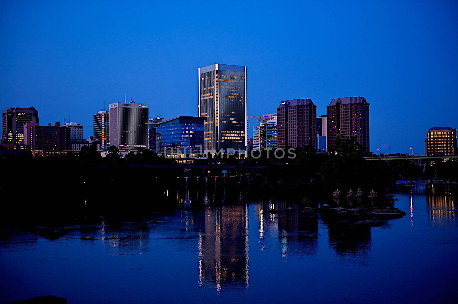 Richmond, Virginia city skyline at night with reflection in the water of the James River.
